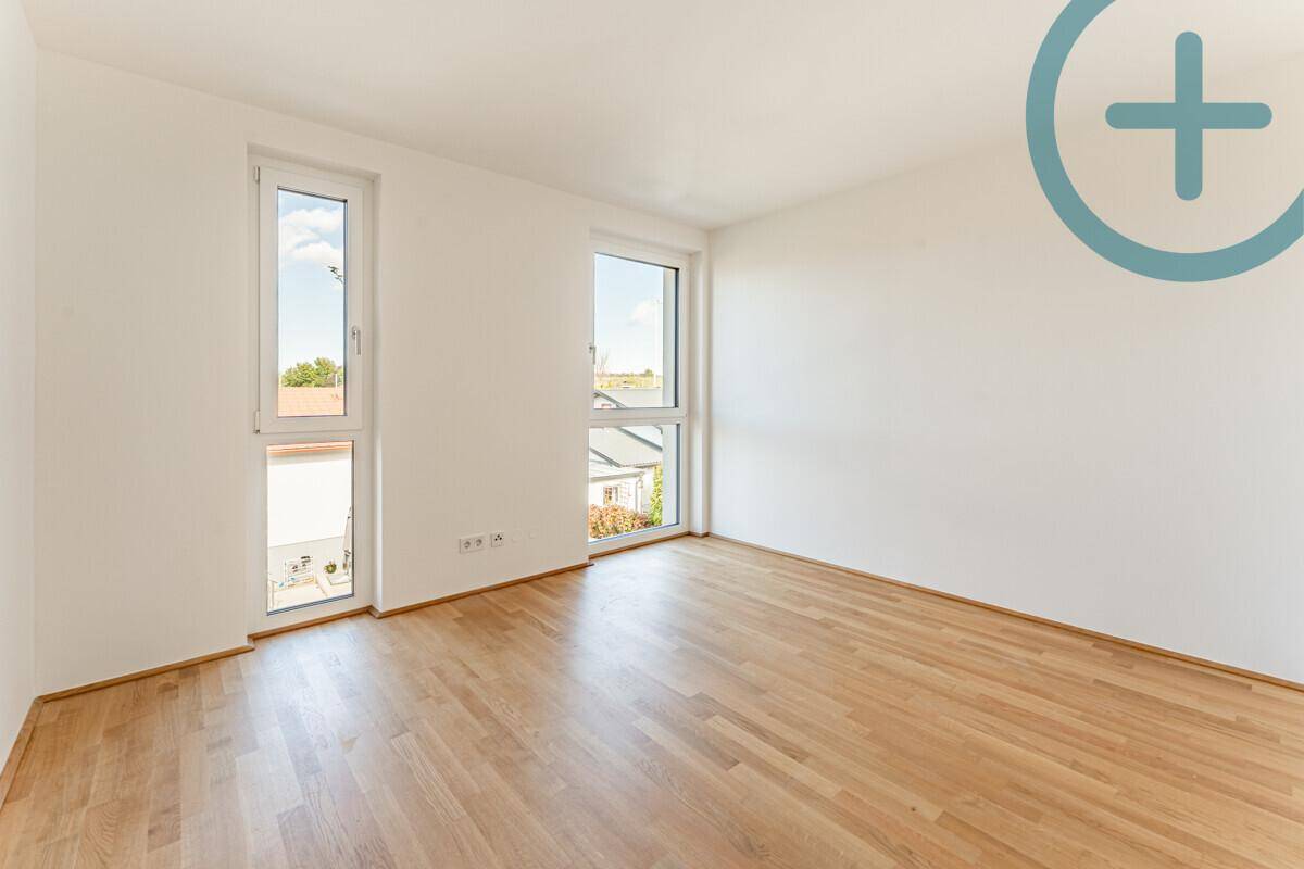 Helles Zimmer mit zwei hohen Fenstern und Parkettboden, bietet viel Tageslicht.