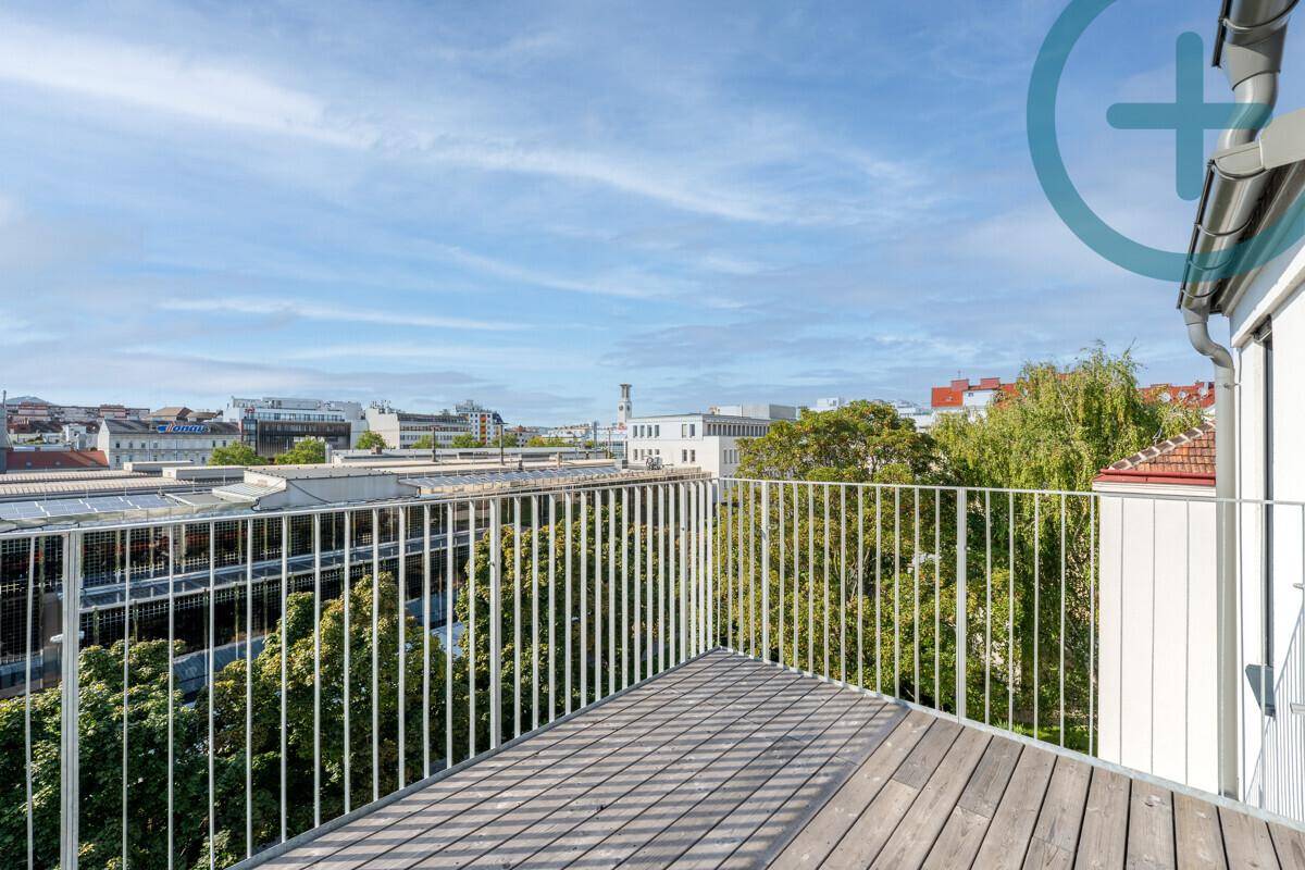 Geräumiger Balkon mit Holzboden und Metallgeländer, der einen weiten Blick über die Stadt bietet.