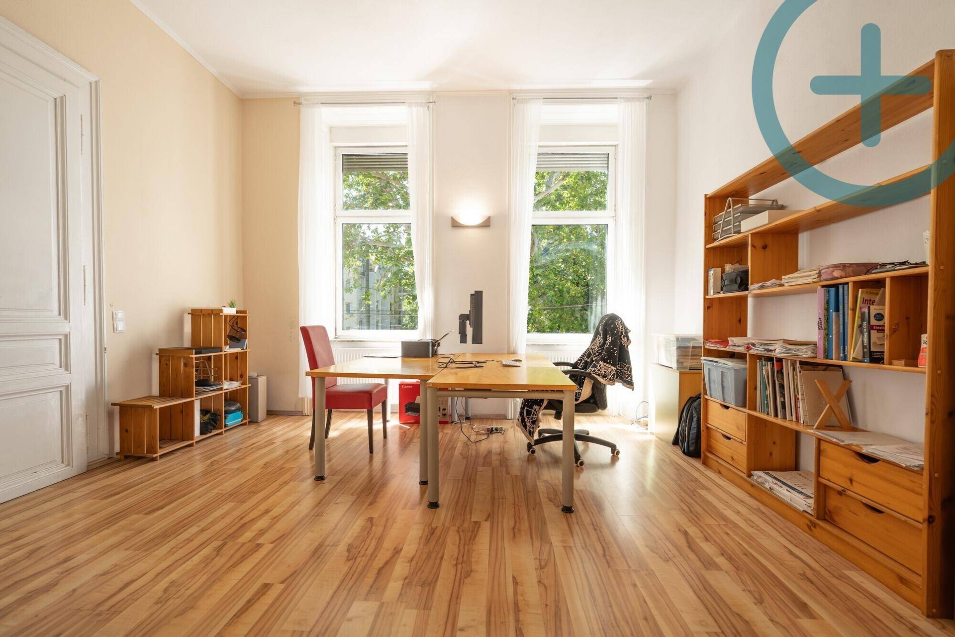 Helles Arbeitszimmer mit Laminatboden, großem Schreibtisch und Bücherregal.