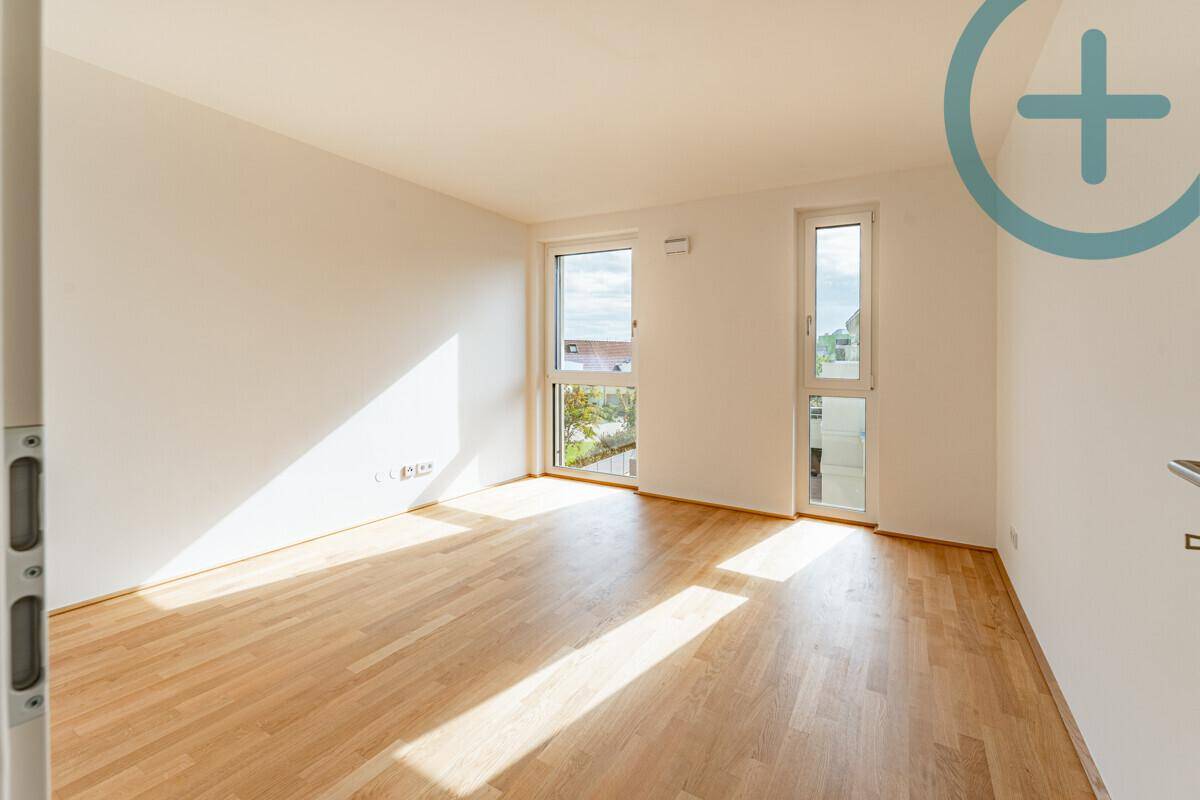 Lichtdurchflutetes Schlafzimmer mit zwei Fenstern und hellem Parkettboden, bietet eine angenehme Atmosphäre.