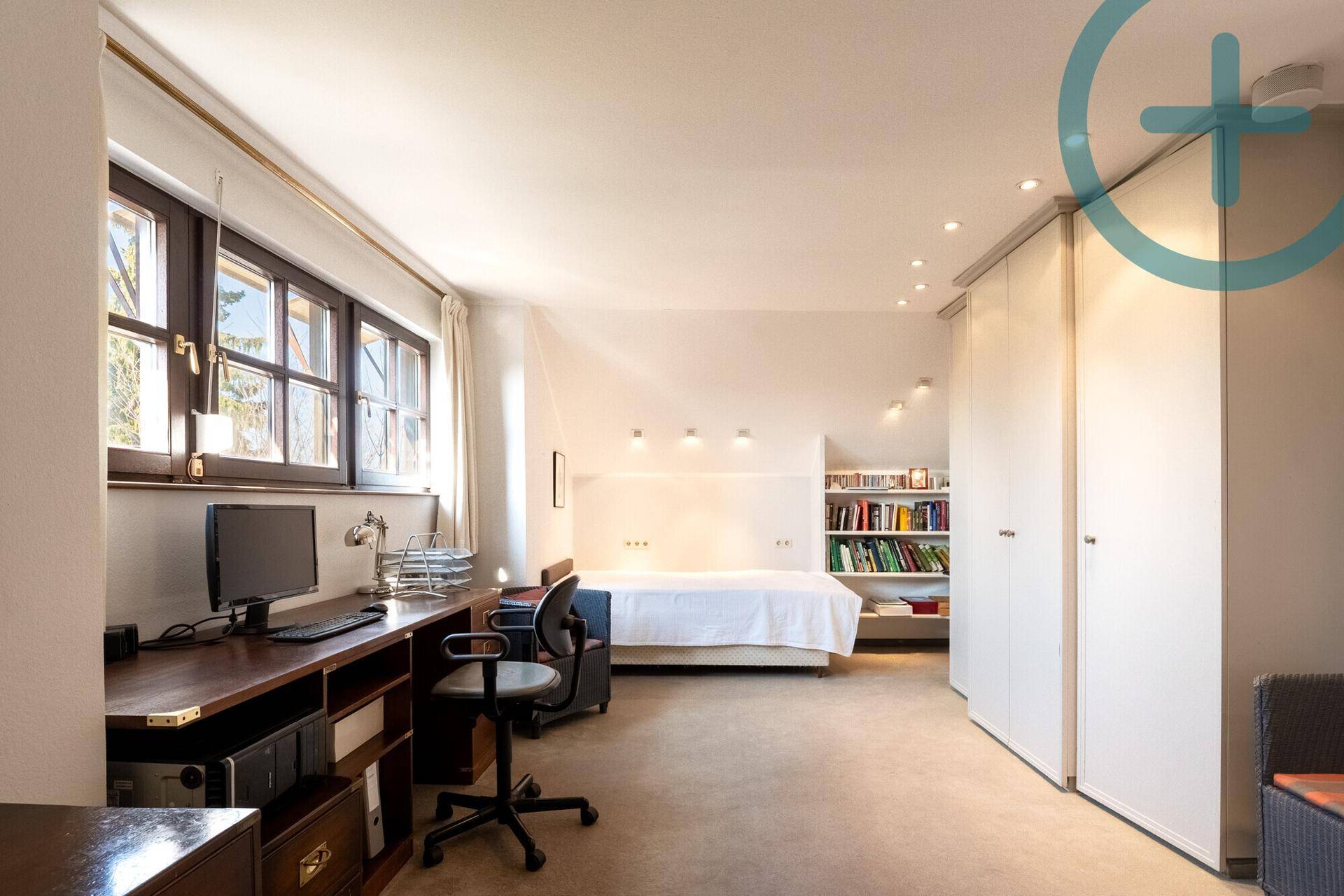 Geräumiges Schlafzimmer mit integriertem Arbeitsbereich, Einbauschränken und Teppichboden.