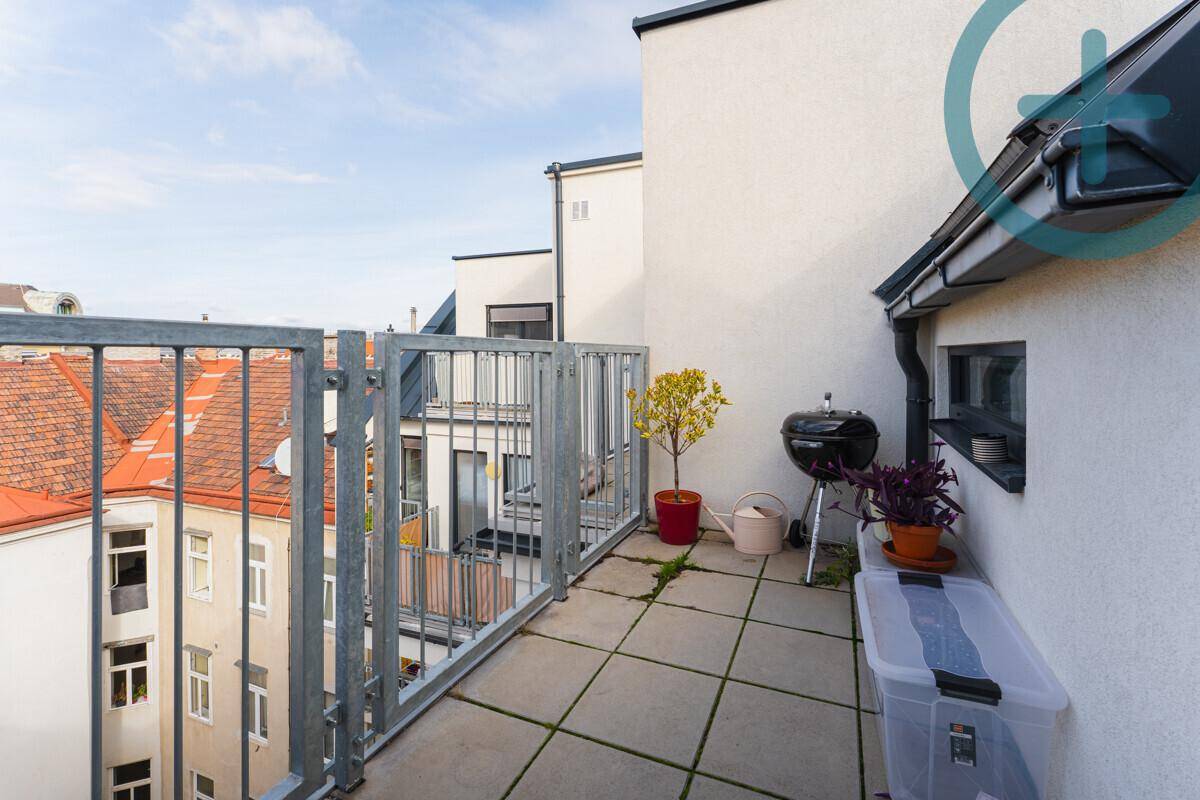 Geräumige Dachterrasse mit Grillbereich und Blick auf die umliegenden Dächer der Stadt.