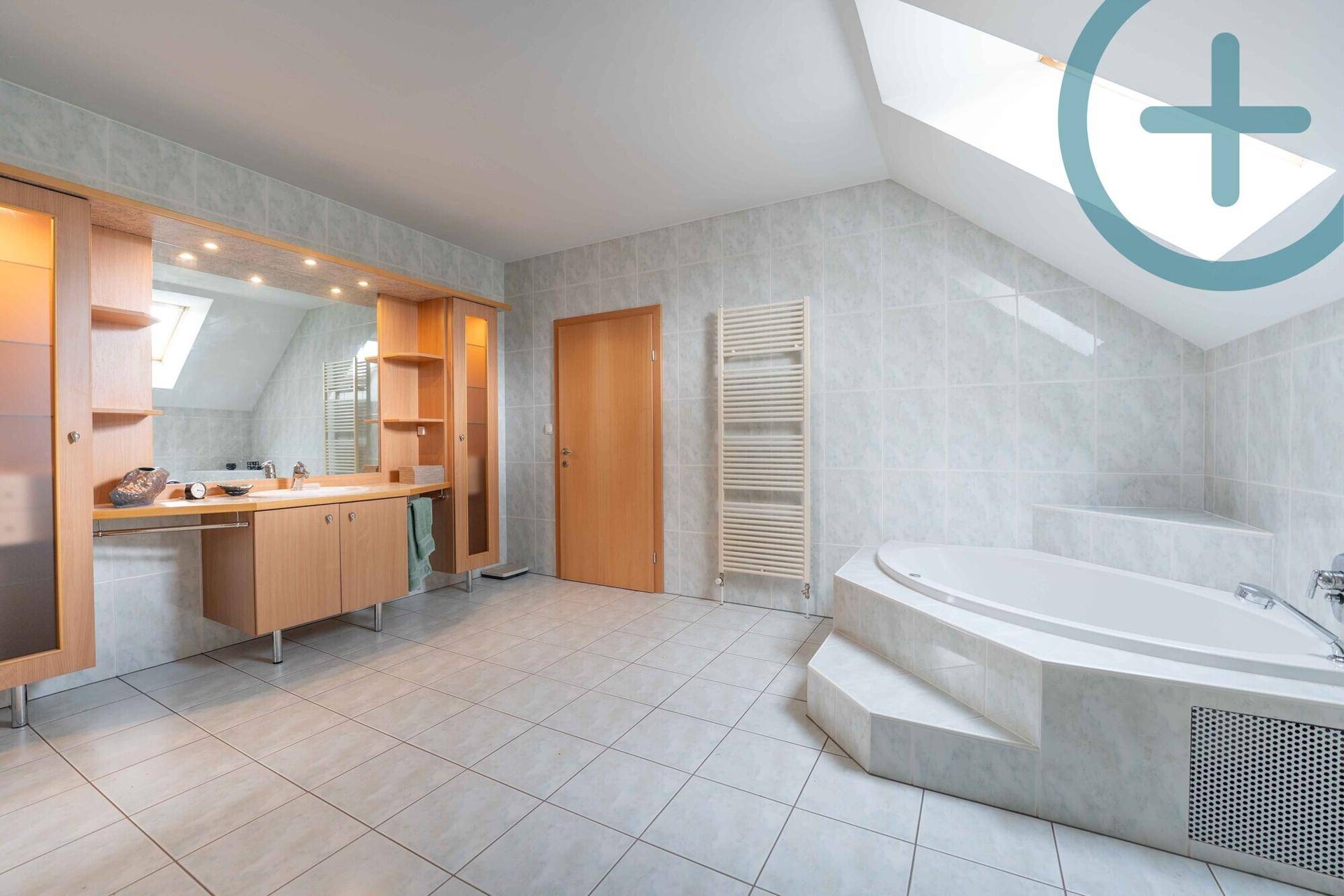 Geräumiges Badezimmer im Dachgeschoss mit Eckbadewanne, Doppelwaschbecken und beheiztem Handtuchhalter.