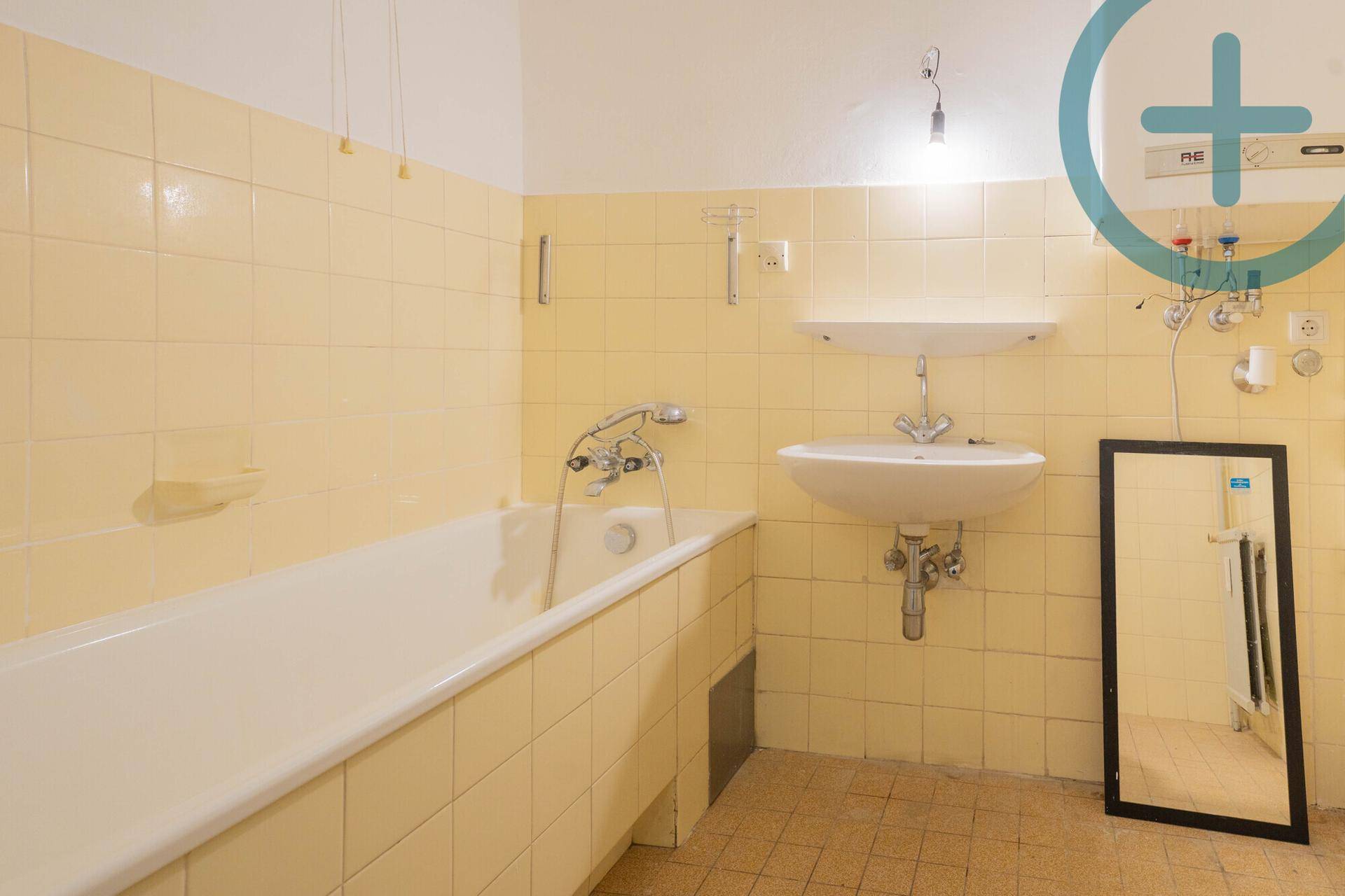 Badezimmer mit gelben Fliesen, Badewanne und Waschbecken, im Stil der 80er Jahre.