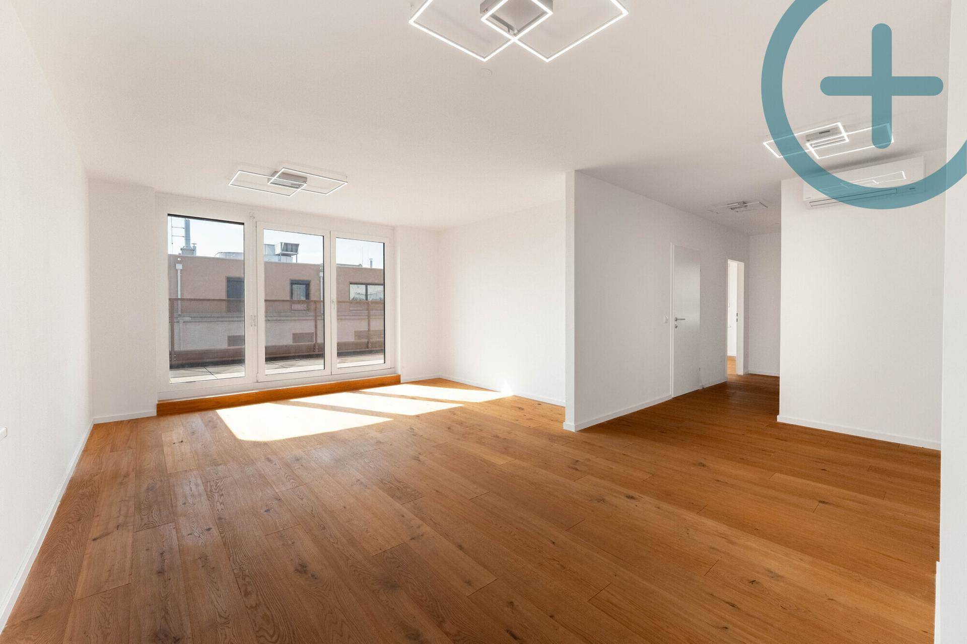 Helles, leeres Zimmer mit breiten Holzplankenböden und großen Fenstertüren zum Außenbereich.