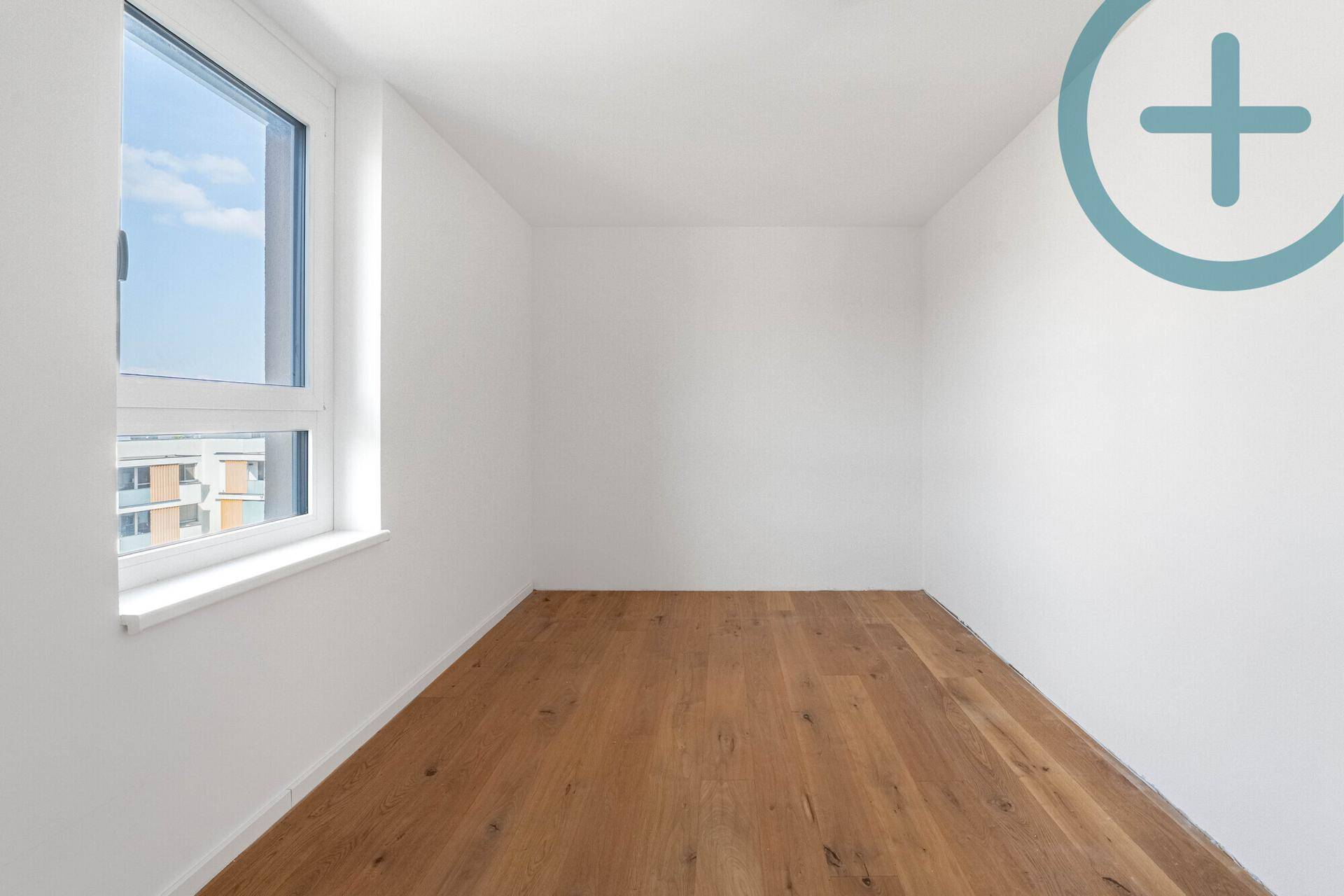 Kleines, helles Zimmer mit Holzplankenboden und einem Fenster, ideal als Kinder- oder Arbeitszimmer.