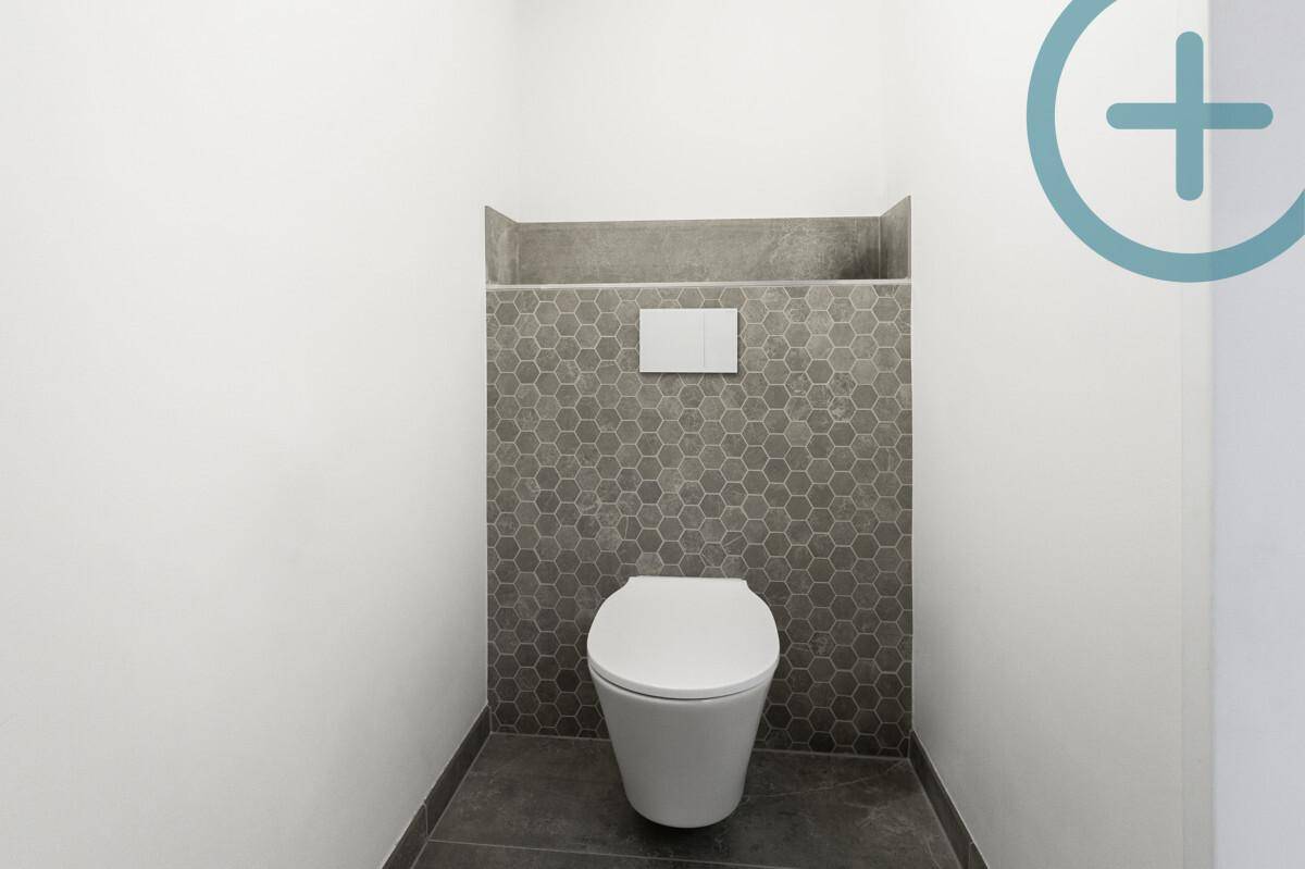 Modernes Gäste-WC mit wandhängender Toilette und stilvollen sechseckigen Fliesen an der Wand.
