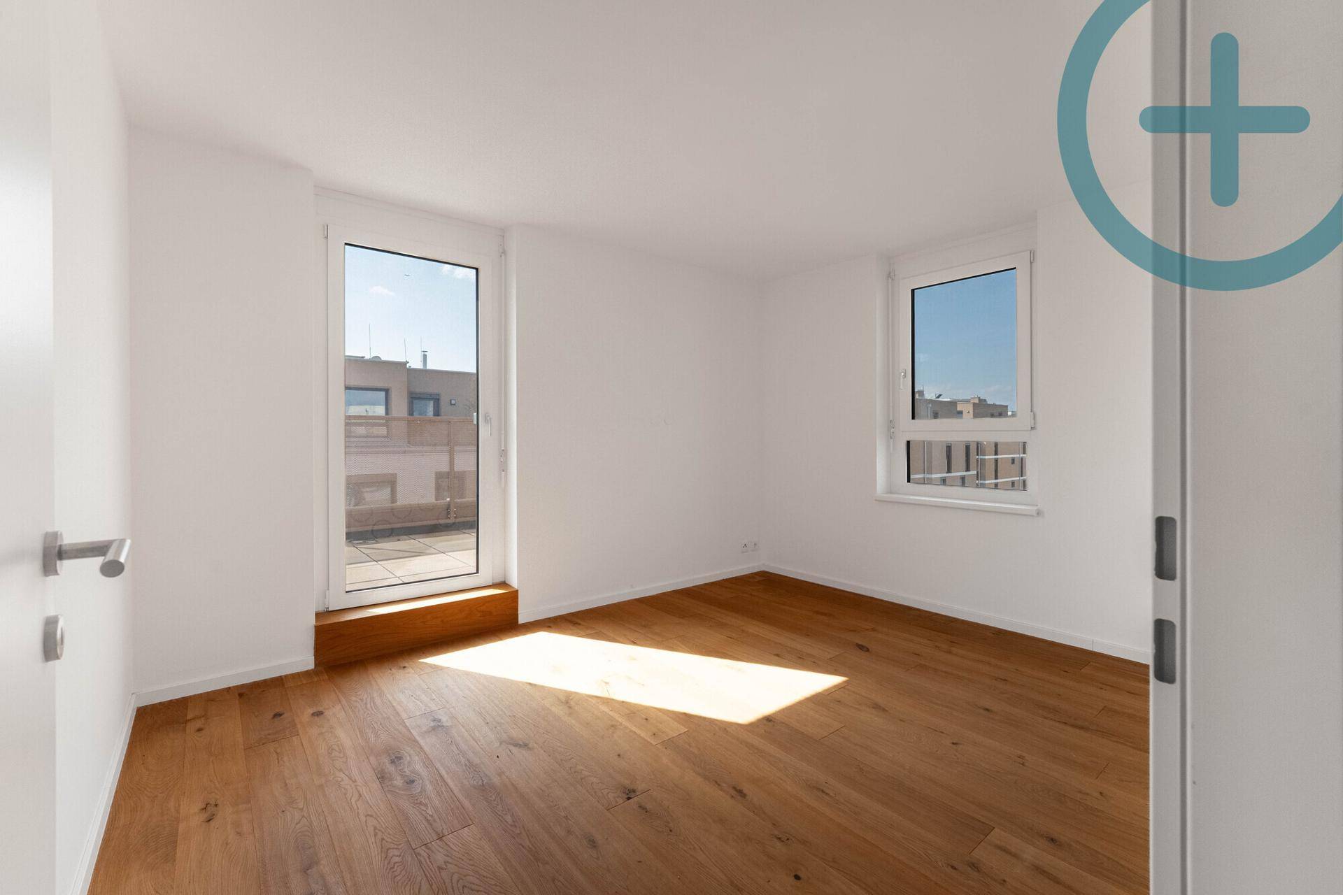Helles Schlafzimmer mit Holzplankenboden, großem Fenster und Zugang zu einem Außenbereich.