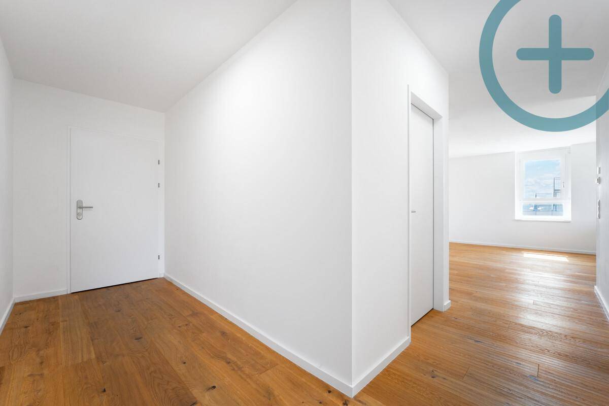 Heller Flur mit Holzplankenboden und weißen Türen, der zu weiteren Räumen führt.