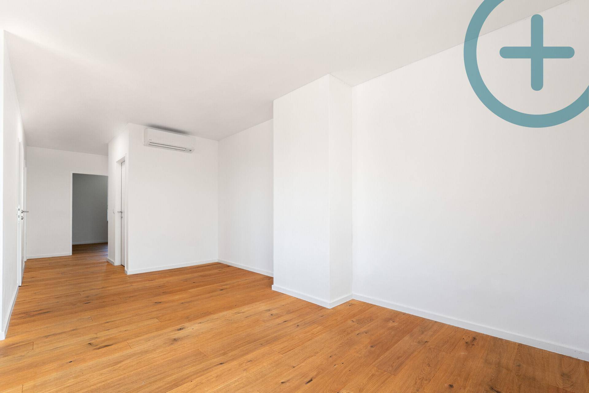 Geräumiger, heller Raum mit Holzplankenboden und integrierter Klimaanlage, ideal für Wohnzwecke.