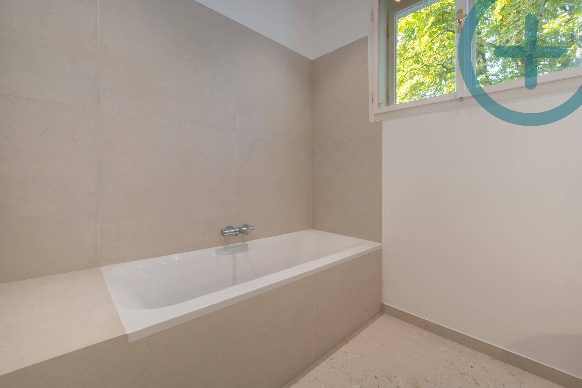 Helles Badezimmer mit integrierter Badewanne und Fenster, modern gefliest.