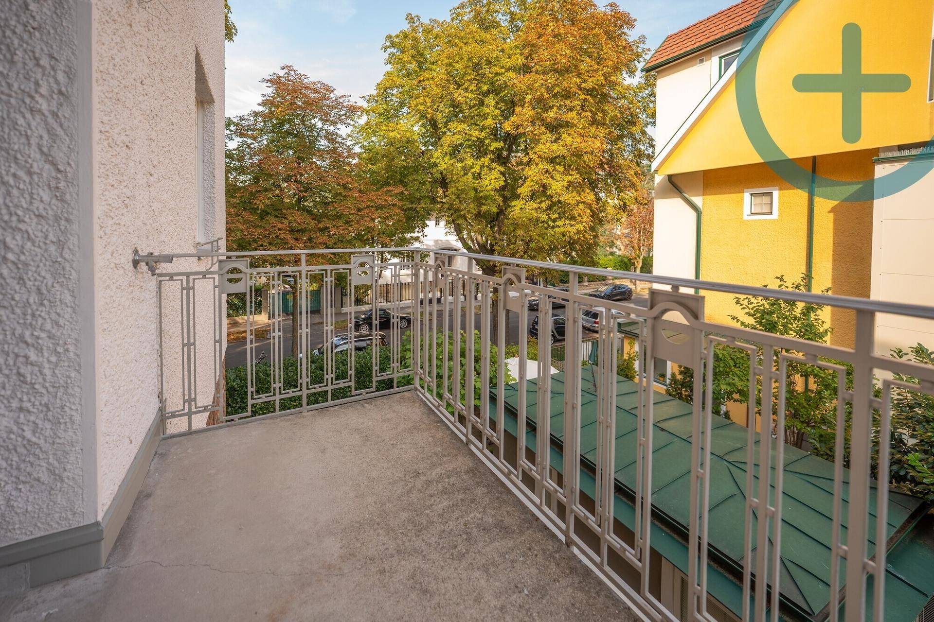 Außenbalkon mit Metallgeländer und Blick auf Bäume und umliegende Gebäude.