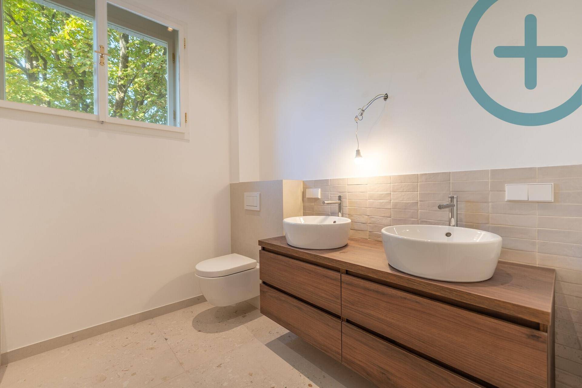 Modernes Badezimmer mit Doppelwaschbecken, schwebendem Unterschrank und Fenster.