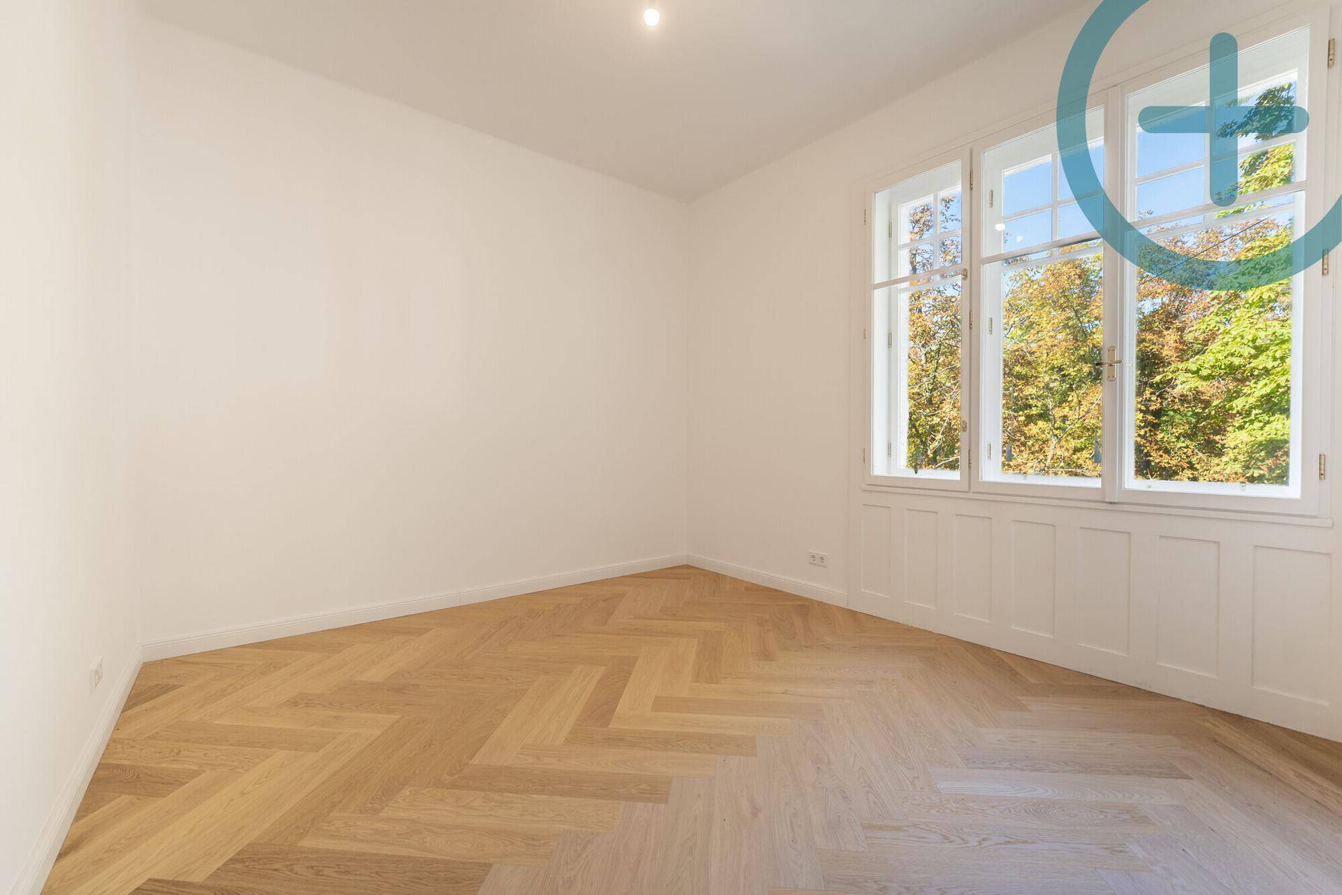 Ruhiges Schlafzimmer mit Fischgrätparkett und großen Fenstern mit Blick ins Grüne.