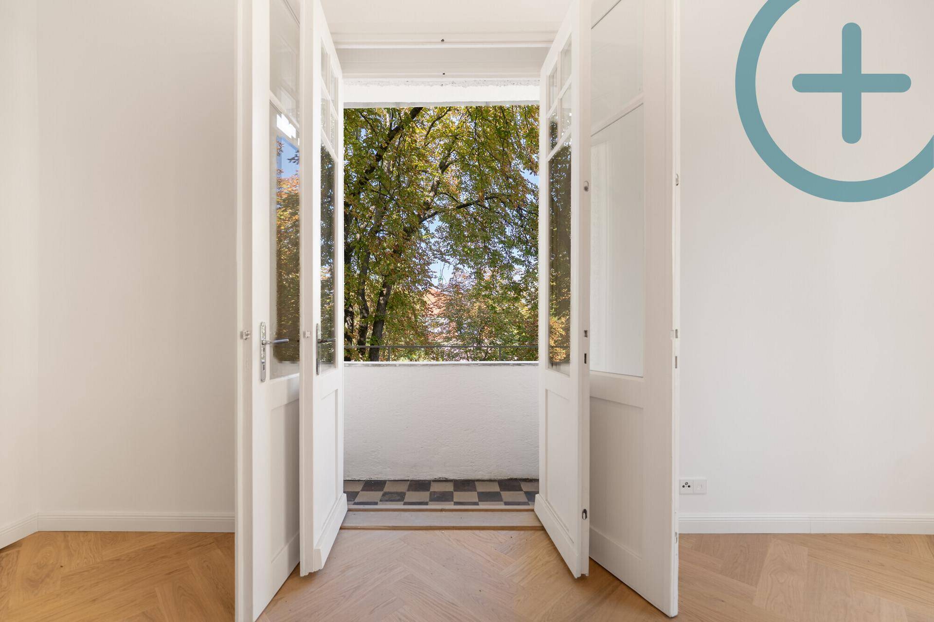 Kleiner Balkon mit karierten Fliesen und Blick auf grüne Bäume.