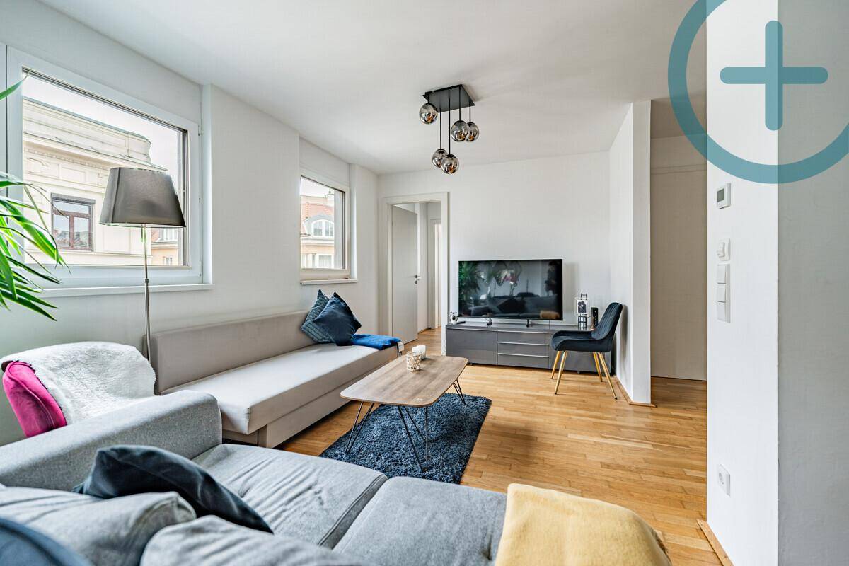 Gemütliches Wohnzimmer mit Holzboden, großem Sofa und Fernseher.
