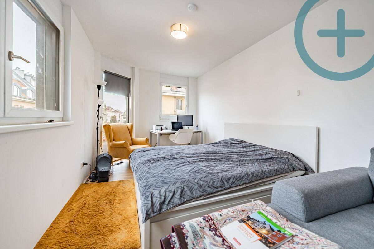 Schlafzimmer mit Doppelbett, Schreibtisch und Blick auf die Stadt.
