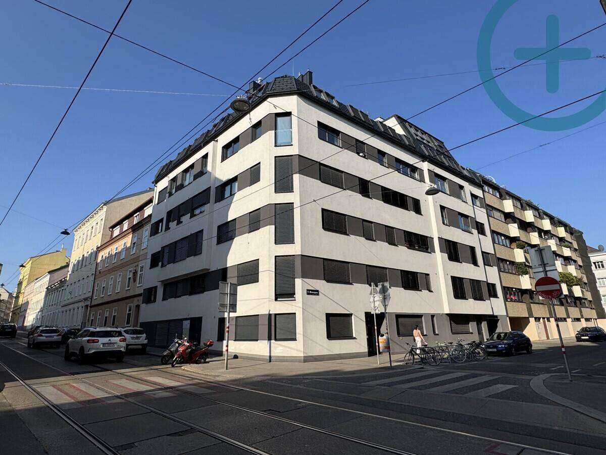 Modernes Eckgebäude in städtischer Umgebung mit vielen Fenstern und Jalousien.