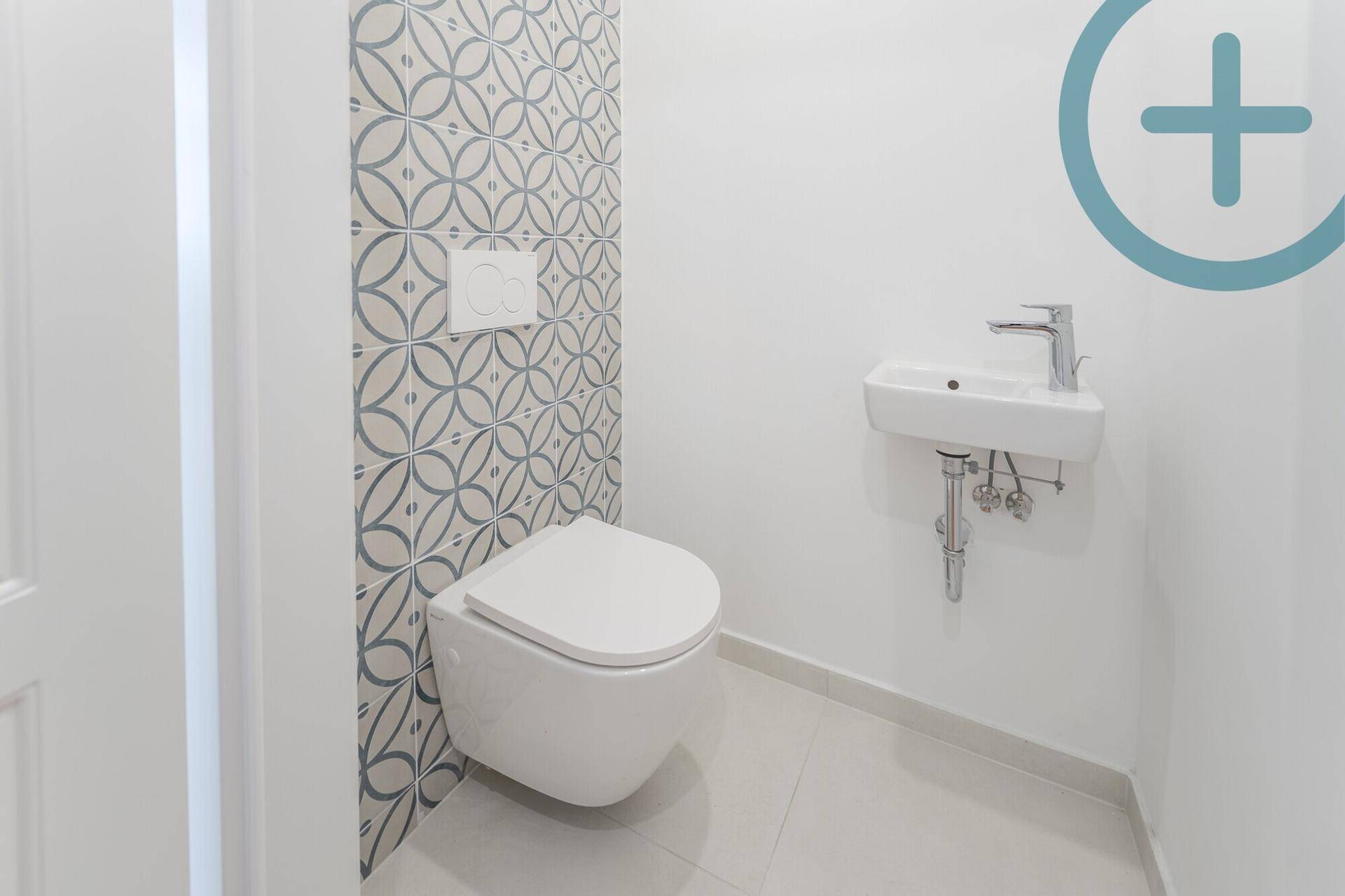Modernes Gäste-WC mit Wand-WC und kleinem Waschbecken, akzentuiert durch gemusterte Fliesen.