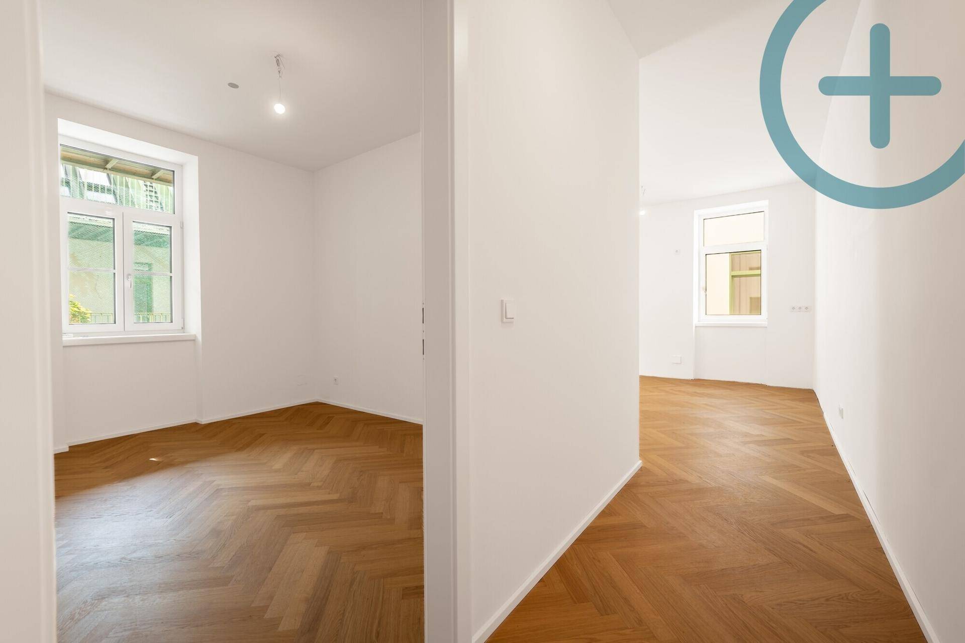 Heller Flur mit Fischgrätparkett, der zu verschiedenen Zimmern der Wohnung führt.