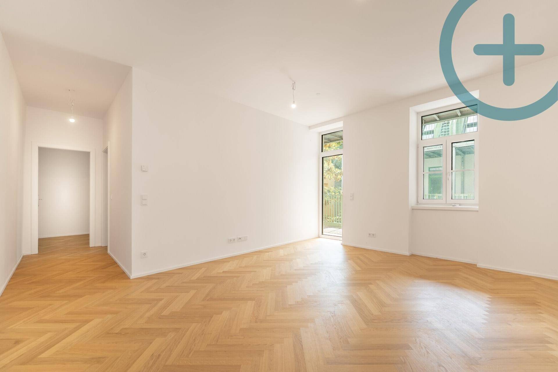 Geräumiges, helles Zimmer mit Fischgrätparkett und großen Fenstern, bereit zur Einrichtung.