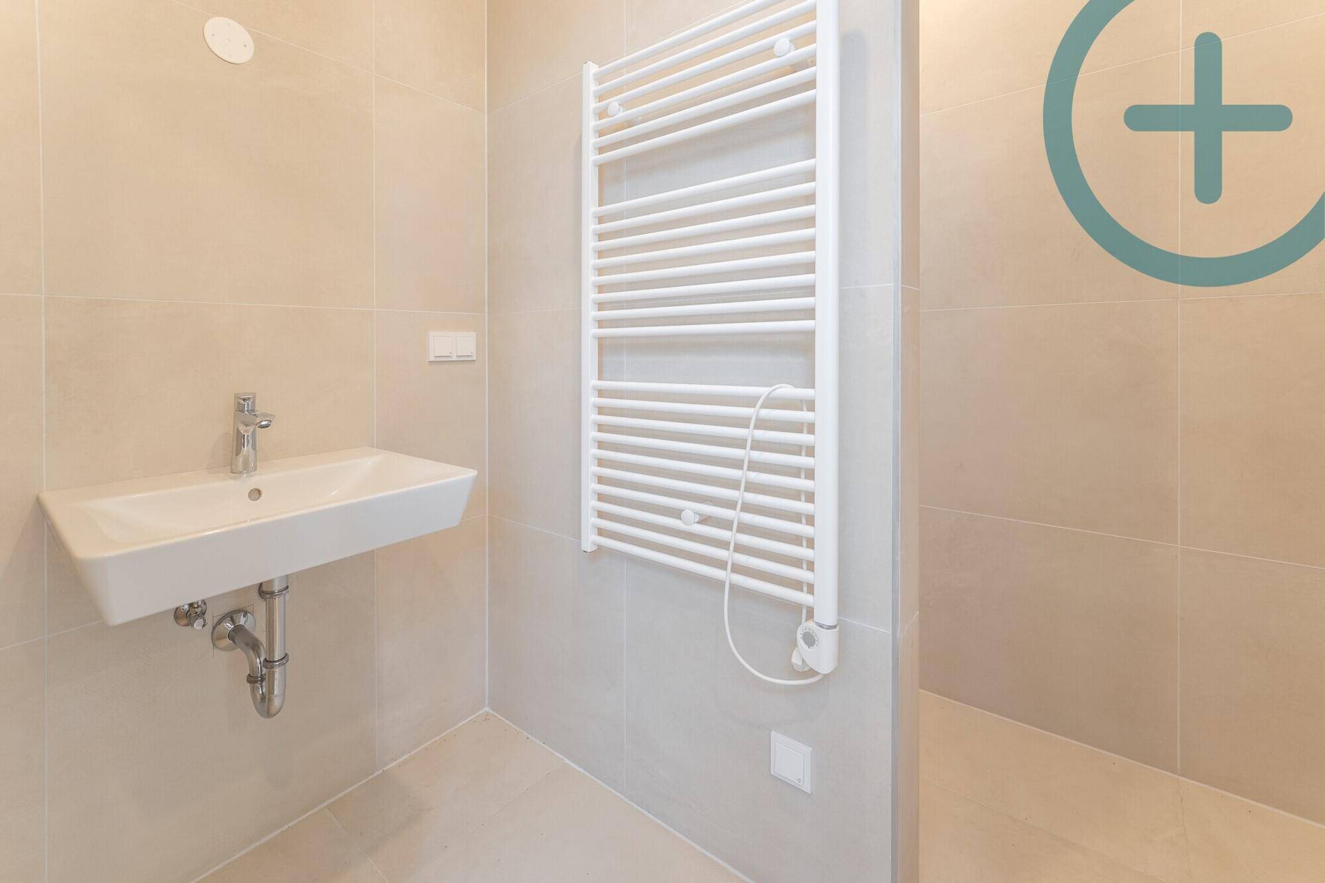 Modernes Badezimmer mit beigefarbenen Fliesen, Einzelwaschbecken und beheiztem Handtuchhalter.