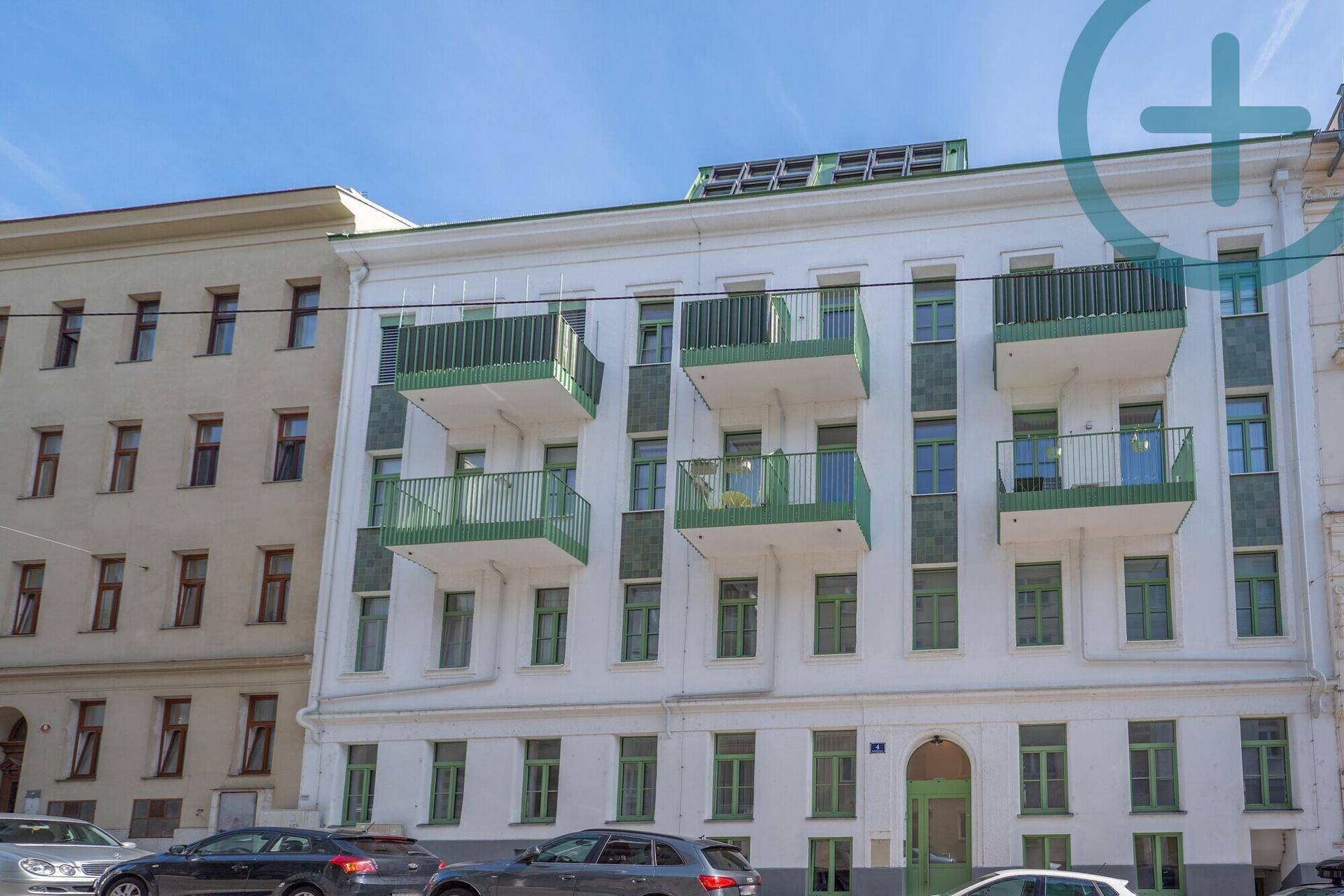 Historisches Gebäude mit weißer Fassade, grünen Fenstern und Balkonen in der Stadt.