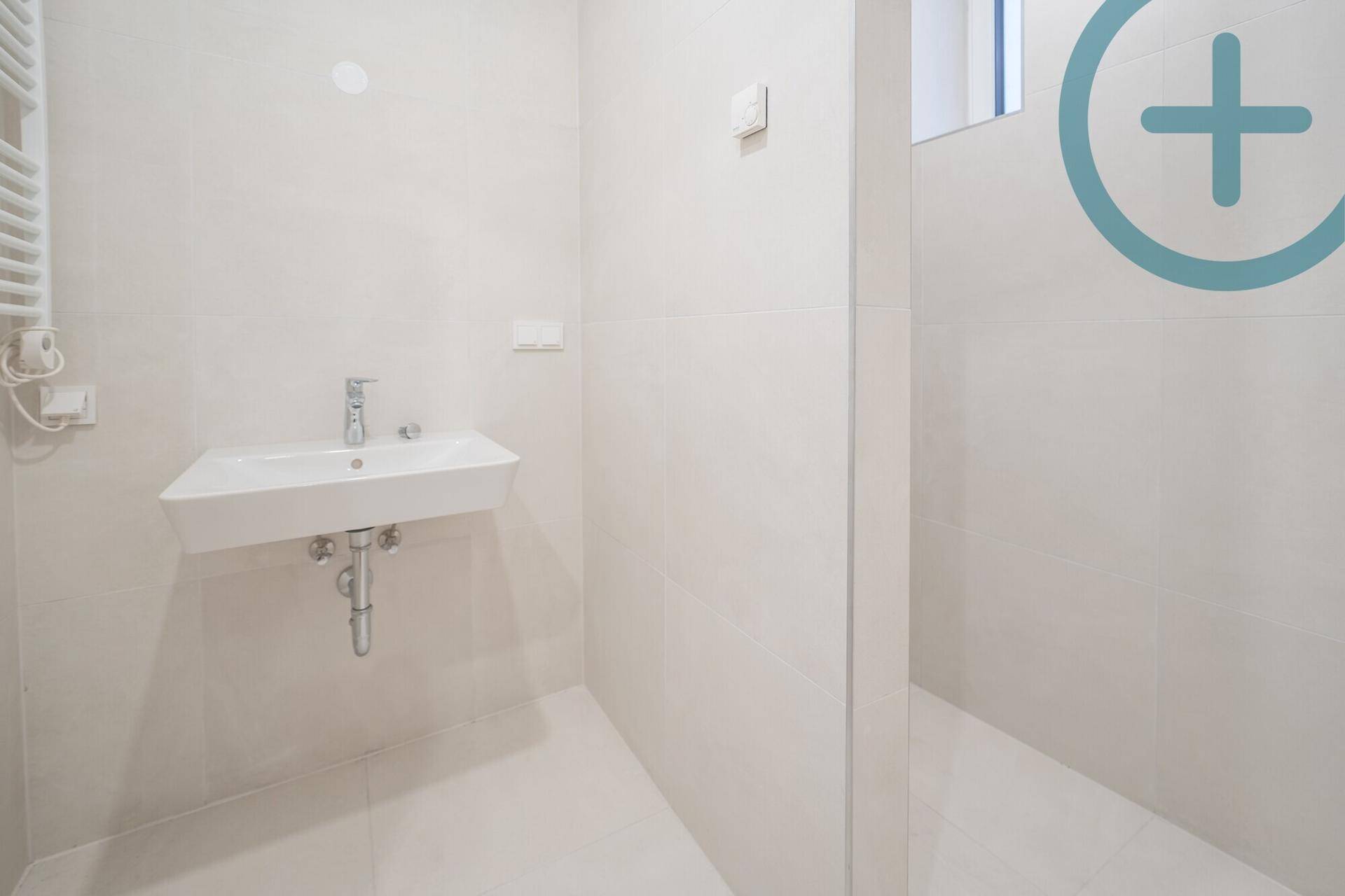 Modernes Badezimmer mit weißem Waschbecken, Fliesenboden und beheiztem Handtuchhalter.