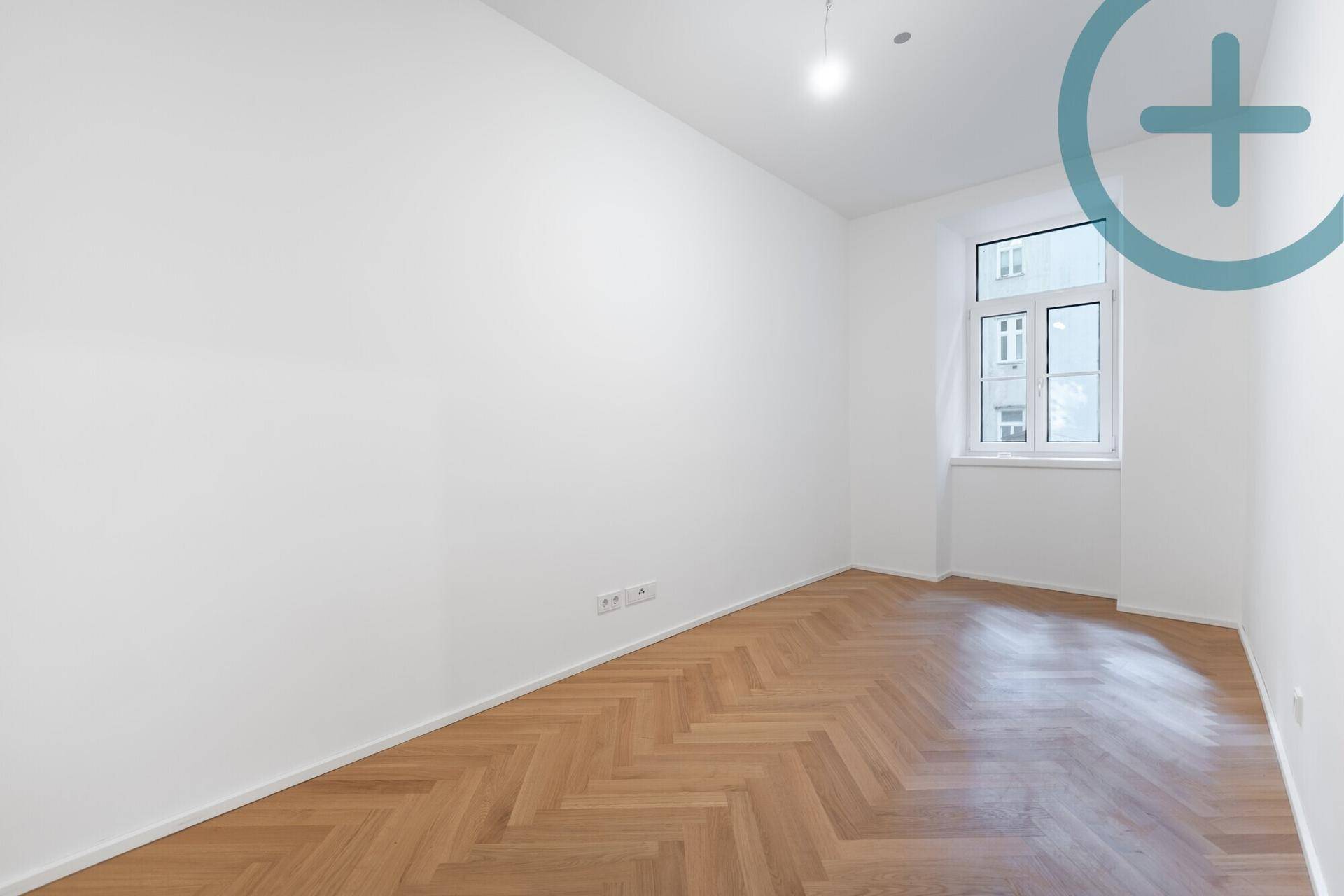Geräumiges, helles Zimmer mit Fischgrätparkett und Fenster, bereit zur individuellen Gestaltung.