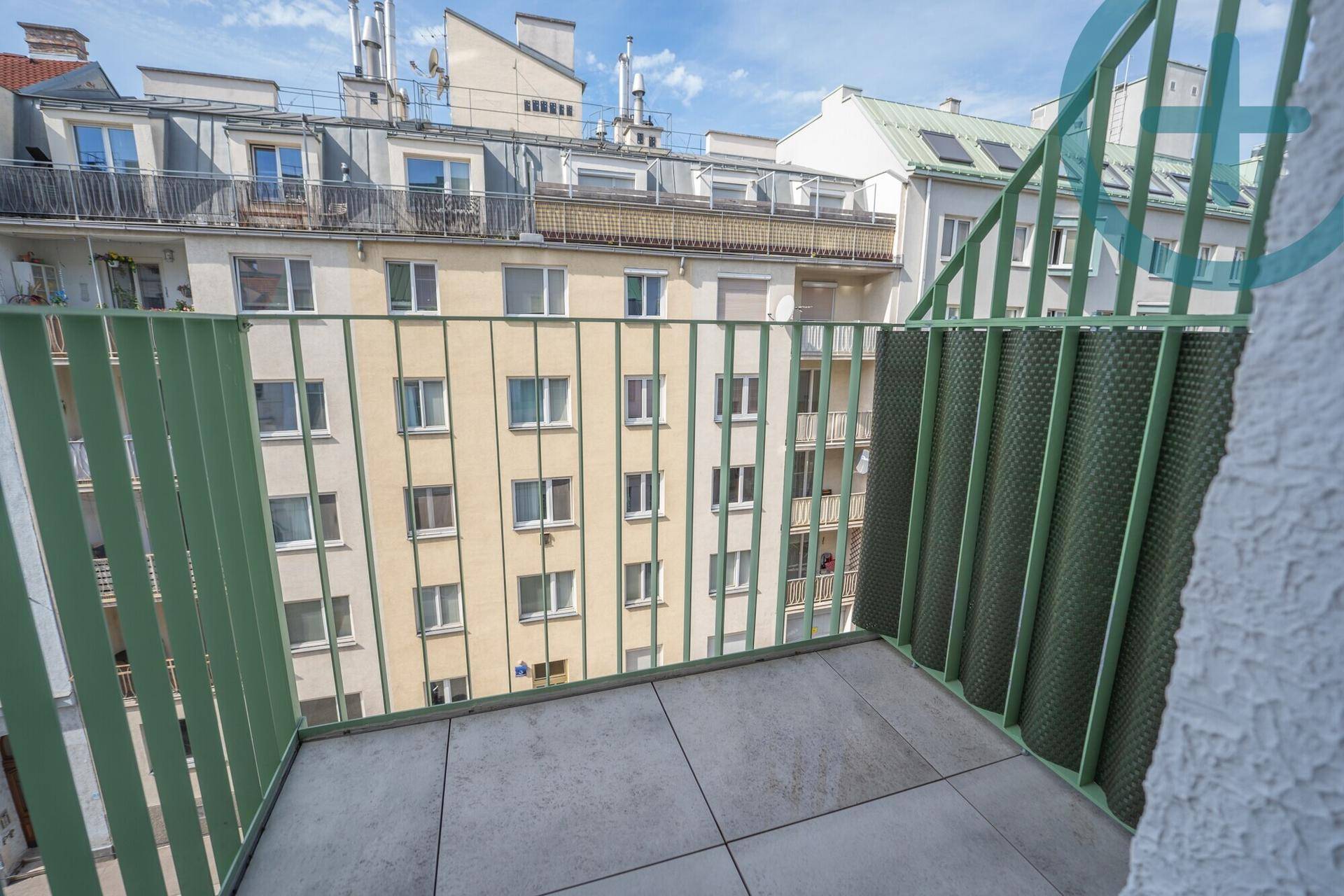 Balkon mit Fliesenboden und Blick auf die umliegenden Stadtgebäude.