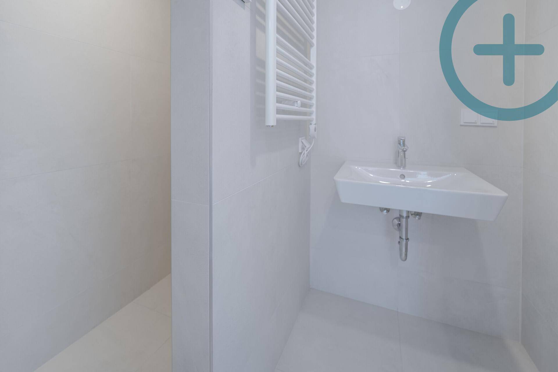 Modernes Badezimmer mit weißen Fliesen, wandhängendem Waschbecken und beheiztem Handtuchhalter.