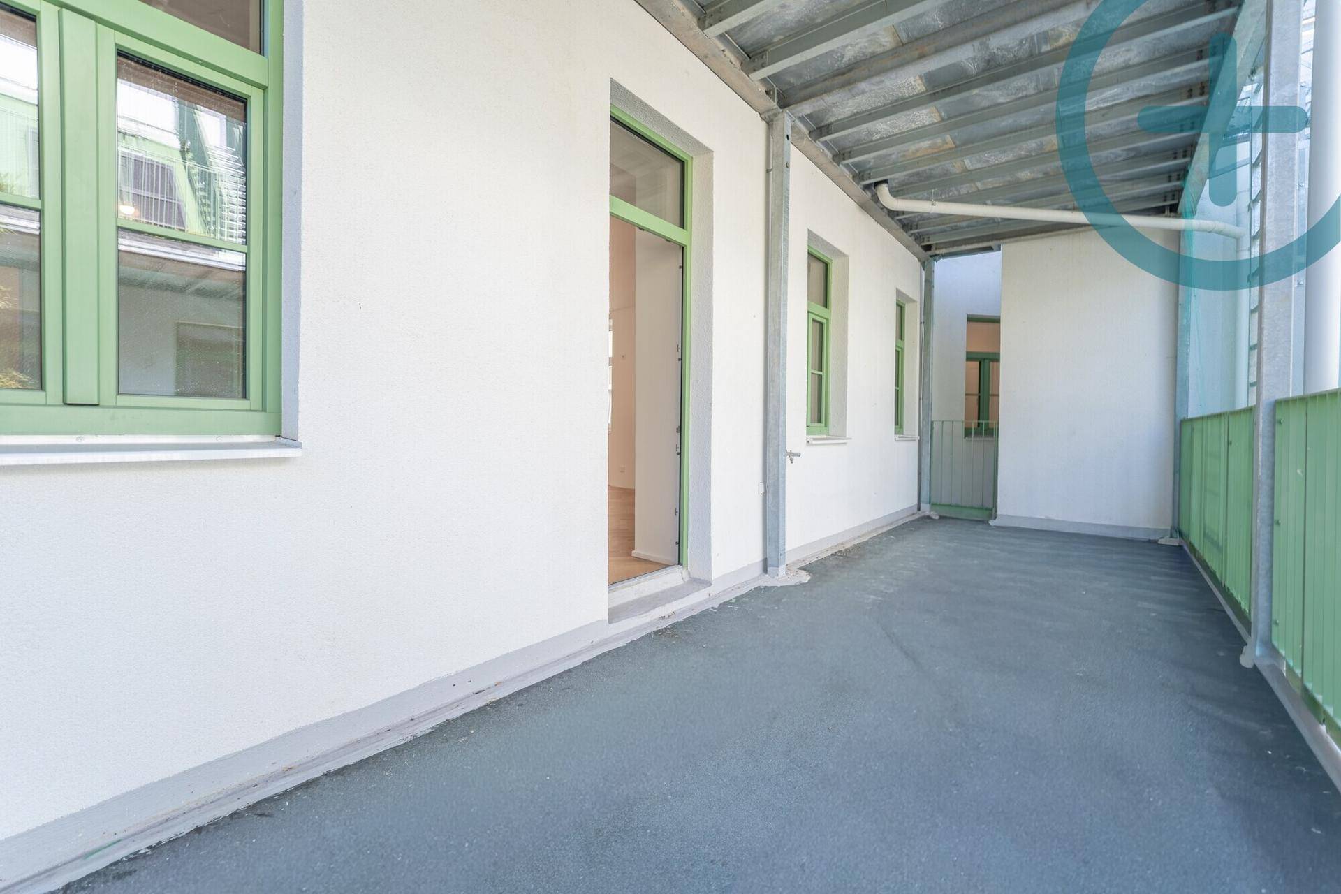 Überdachter Balkon mit grünem Geländer und Blick auf den ruhigen Innenhof.