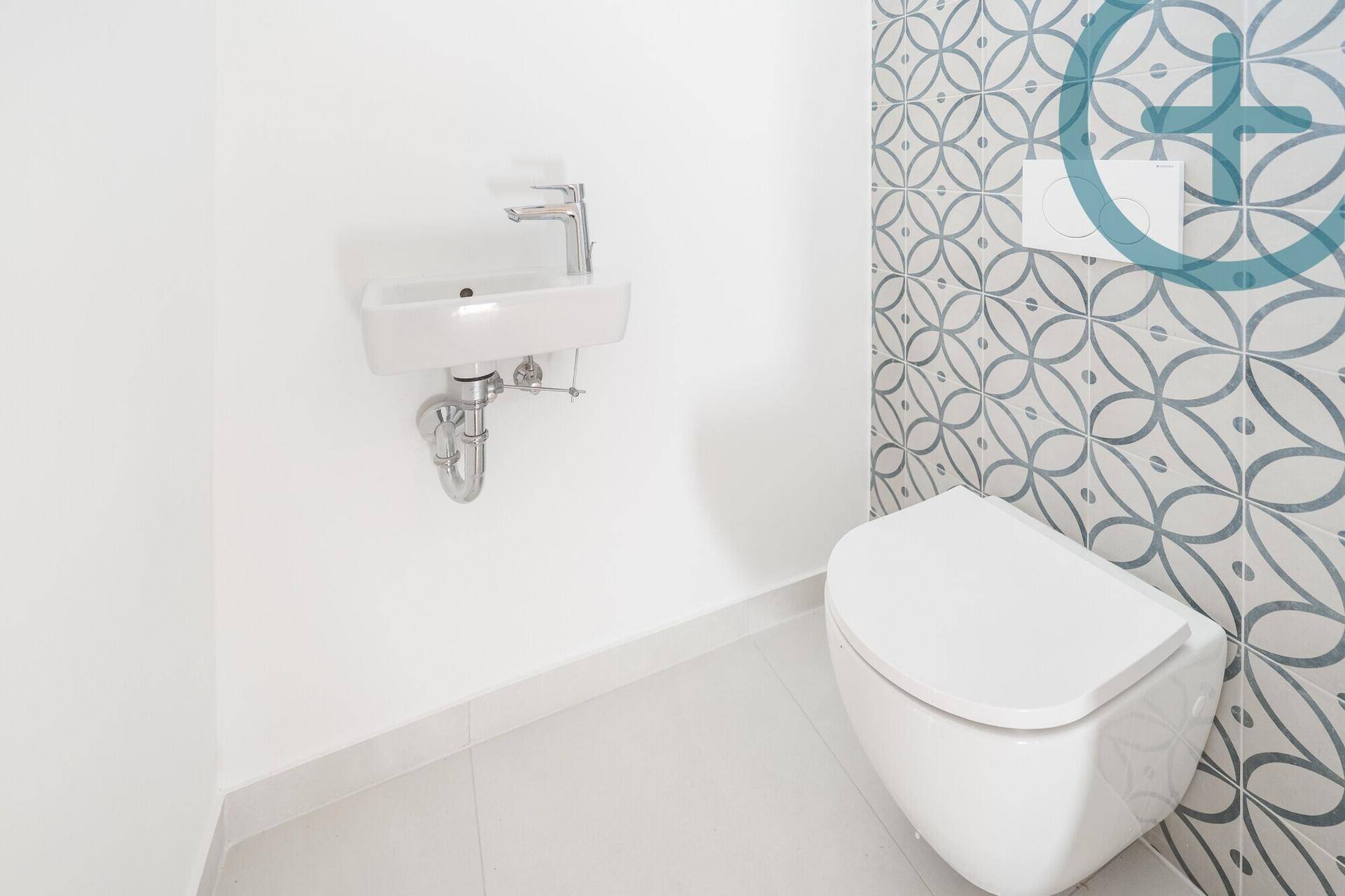 Modernes Gäste-WC mit Wand-WC, kleinem Waschbecken und dekorativen Fliesen, sehr gepflegt.