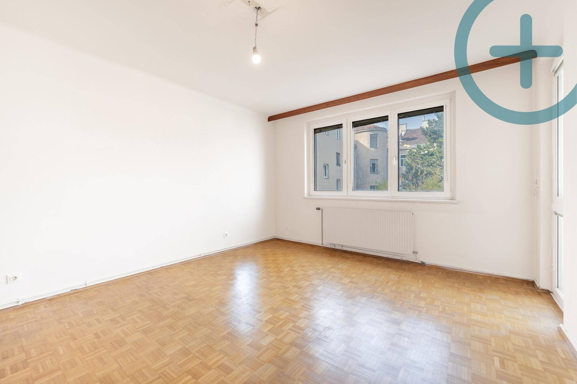 Heller Raum mit Parkettboden, großem Fenster und Heizkörper, ideal als Wohn- oder Schlafzimmer.