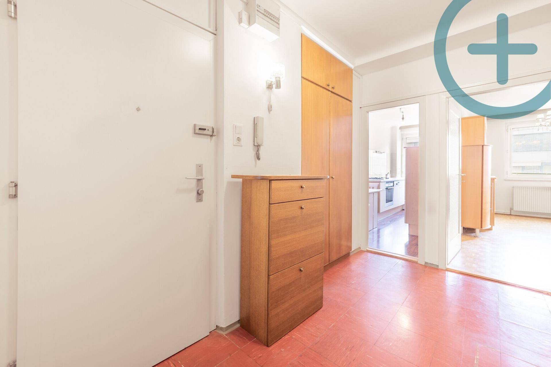 Eingangsbereich mit rotem Fliesenboden, weißer Tür, Holzschuhschrank und Einbauschrank.