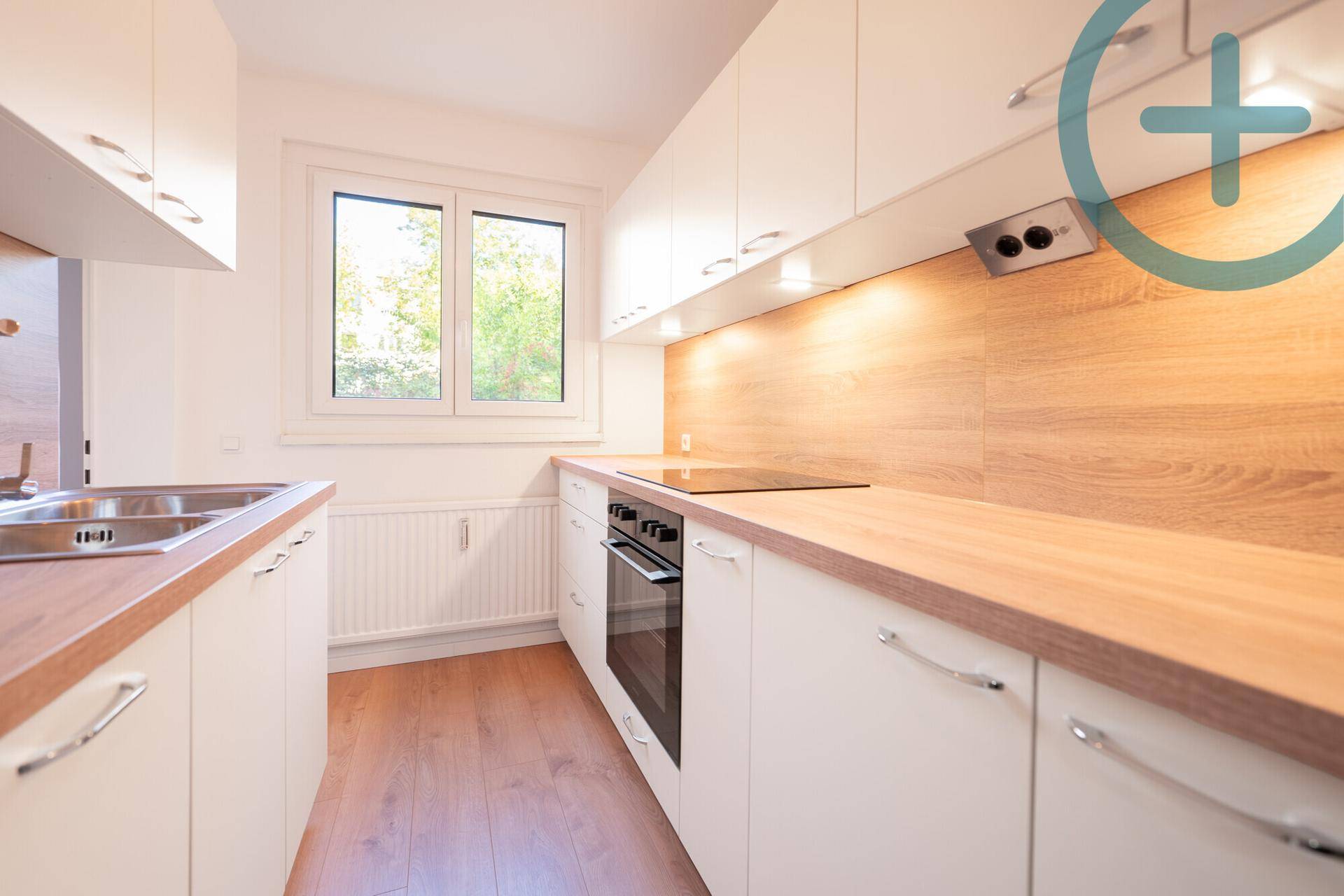 Helle Küche mit weißen Fronten, Holz-Arbeitsplatten und integrierten Geräten.