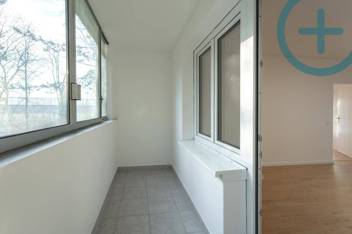 Verglaster Balkon mit Fliesenboden und Blick auf die Umgebung.