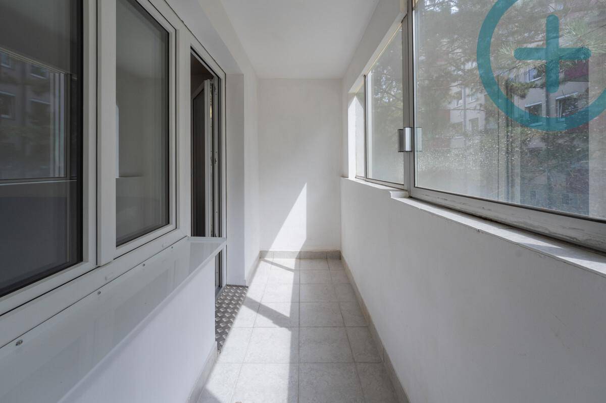 Heller, verglaster Balkon mit Fliesenboden und Blick ins Grüne.