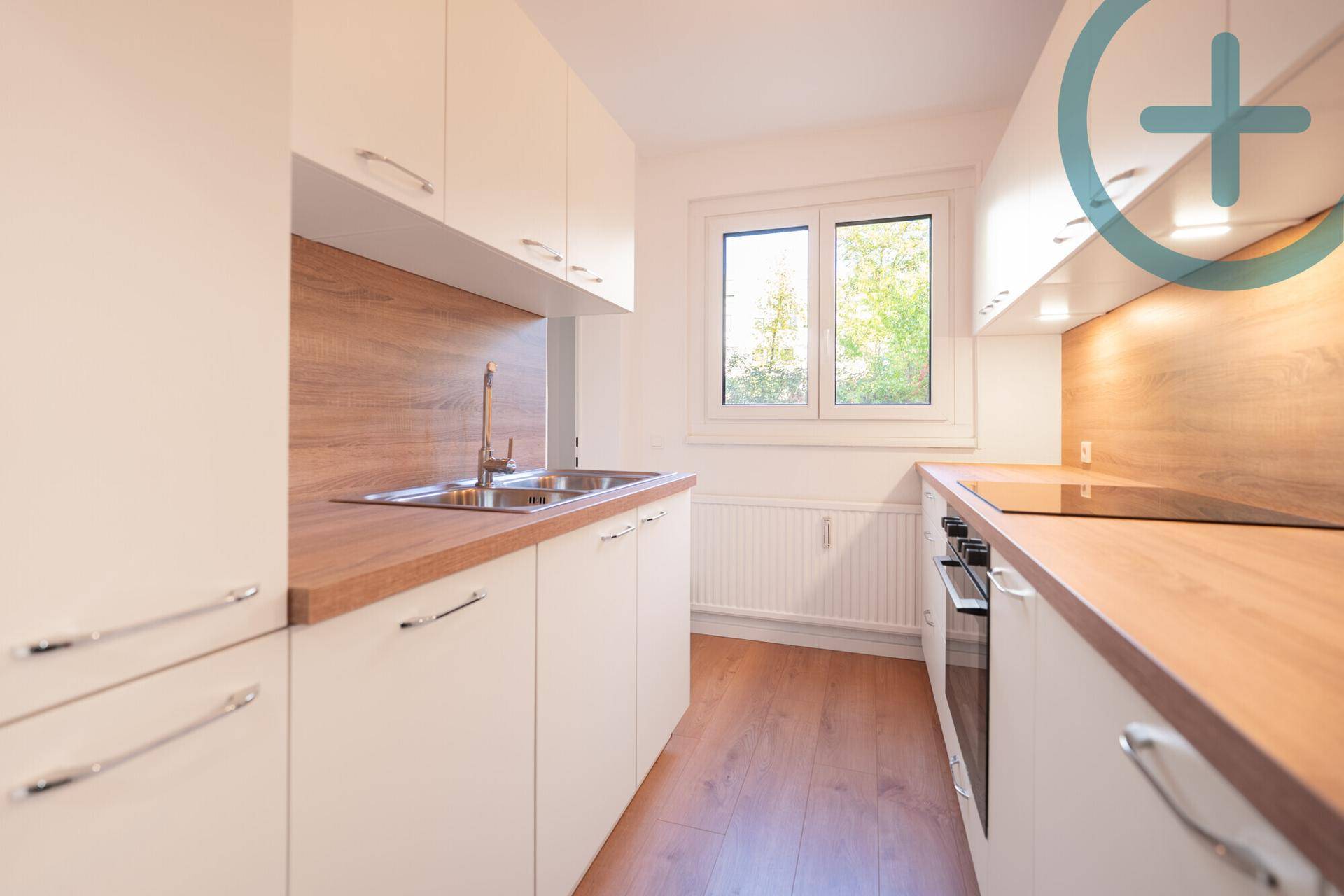 Moderne Einbauküche mit weißen Schränken, Holz-Arbeitsplatten und Fenster.