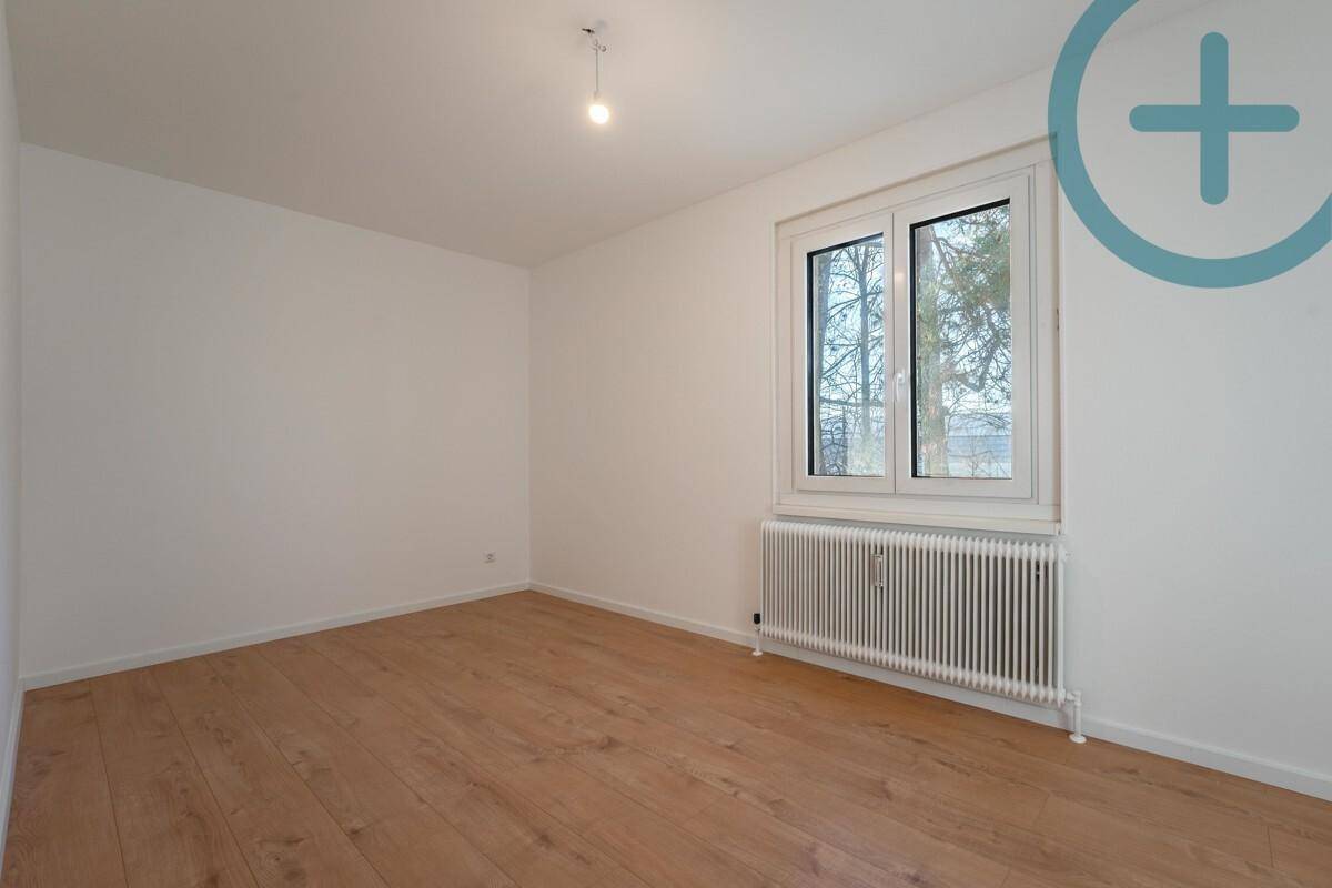 Helles, unmöbliertes Zimmer mit Laminatboden und einem großen Fenster.