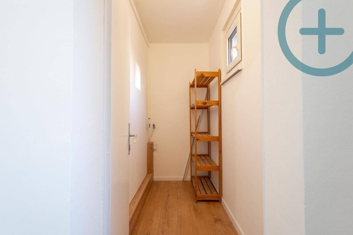 Kleiner Abstellraum mit Holzregal, Fenster und Laminatboden.