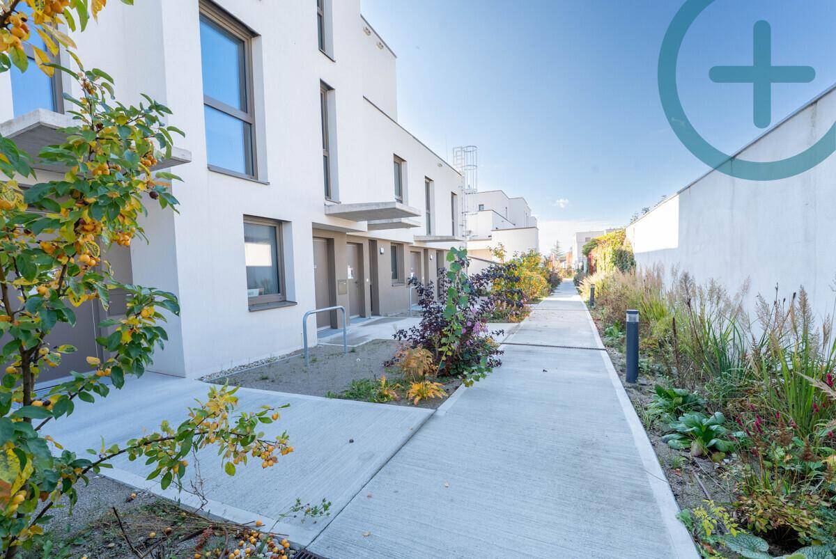Reihe moderner Stadthäuser mit klaren Linien, umgeben von gepflegten Gehwegen und Bepflanzungen.
