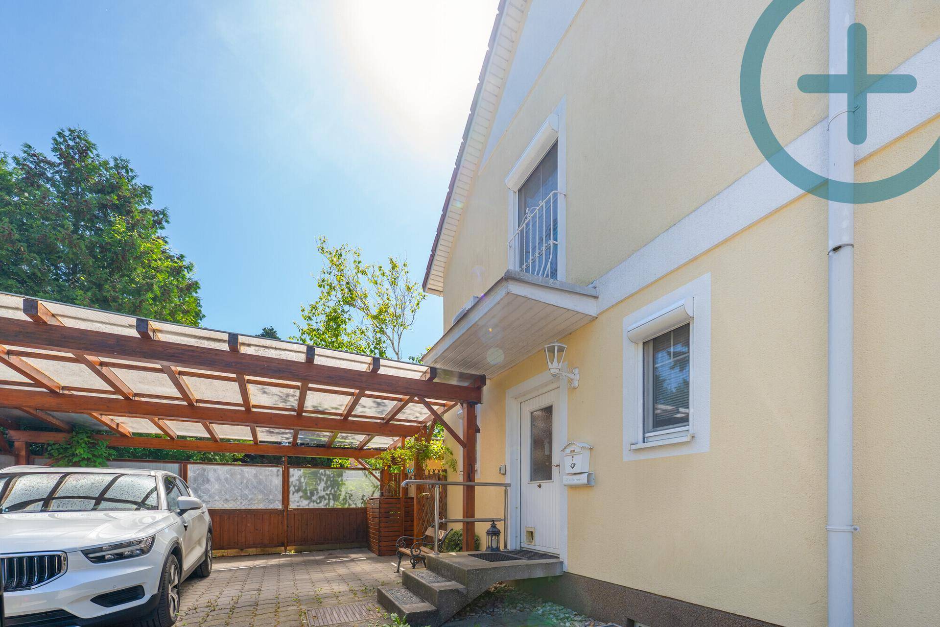 Seitenansicht des Hauses mit Carport und Eingangsbereich unter einem Holzdach.
