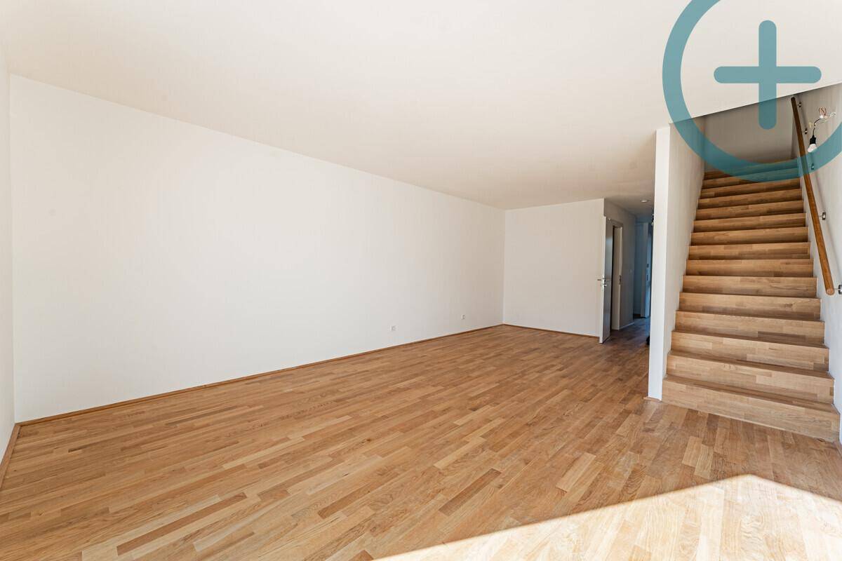 Heller Wohnbereich mit Holztreppe und Parkettboden, bereit für die individuelle Einrichtung.