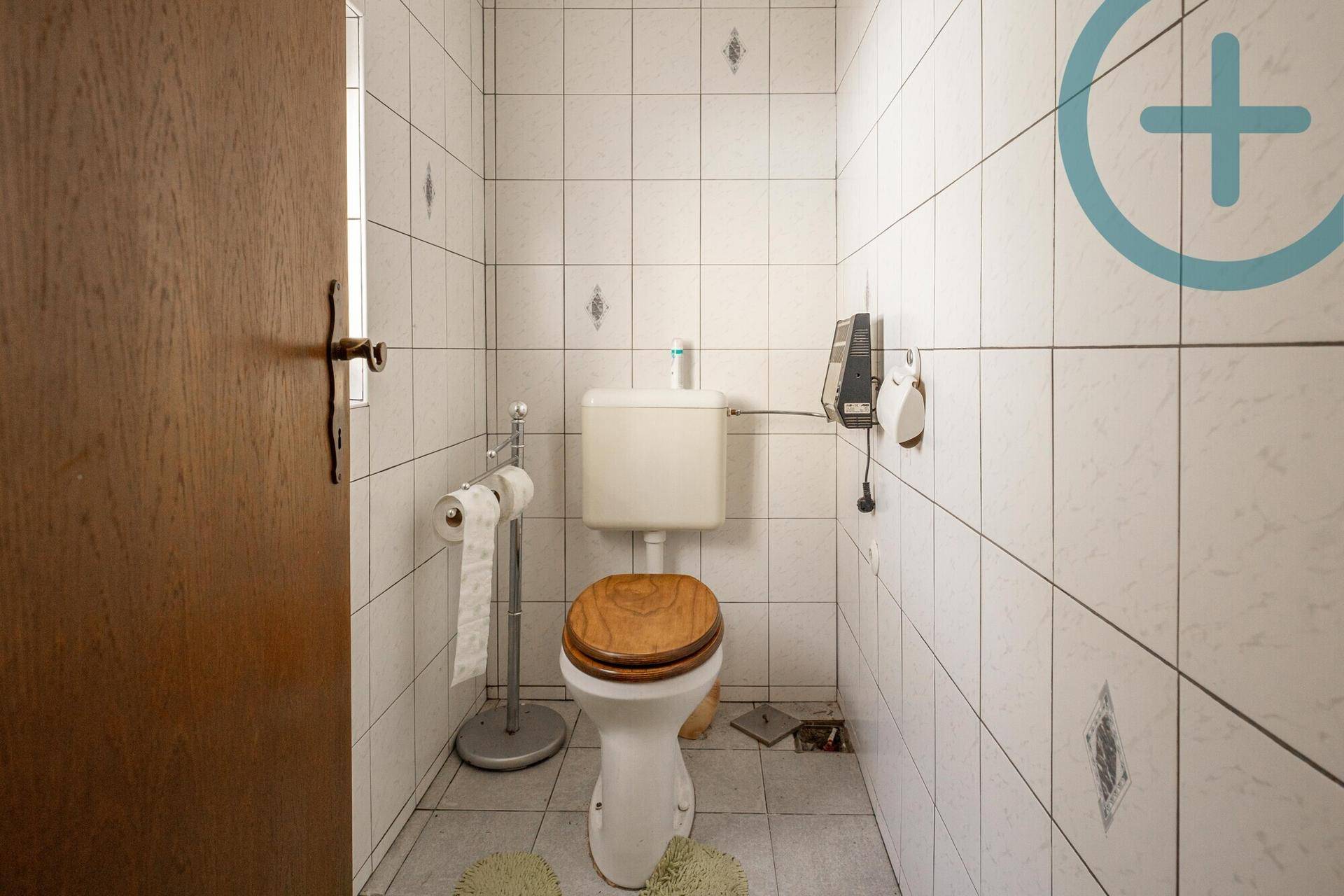 Kleines WC mit weißen Fliesen, Toilette und Holz-Toilettensitz.