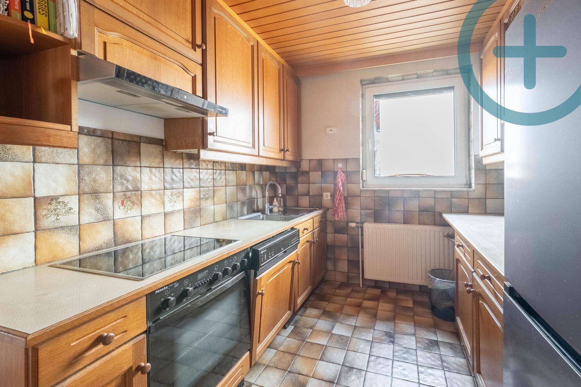 Traditionelle Küche mit Holzschränken, Fliesenboden und integrierten Geräten.