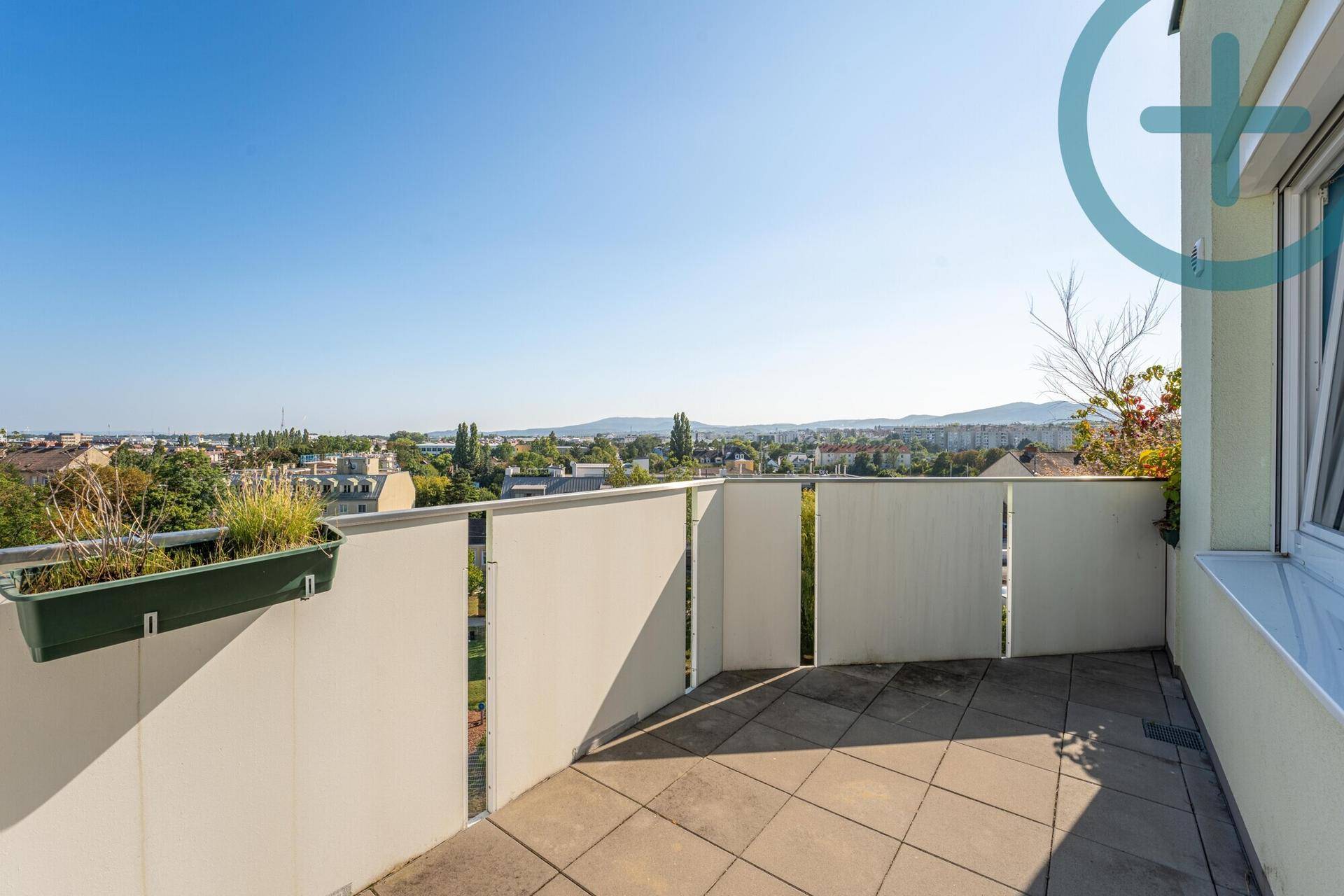 Geräumiger Balkon mit Fliesenboden und weitem Blick über die Stadt und die Berge.