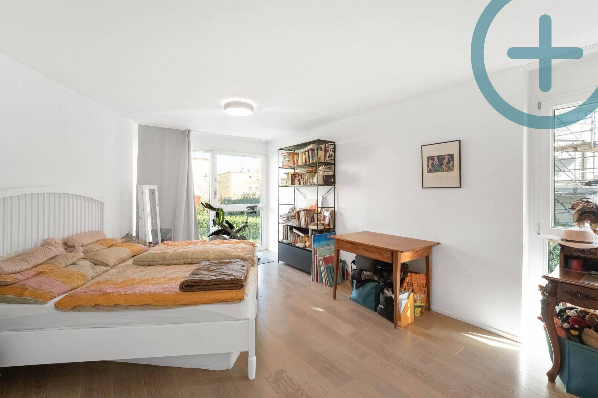 Helles Schlafzimmer mit Holzboden, Doppelbett und Zugang zu einem Balkon oder Garten.