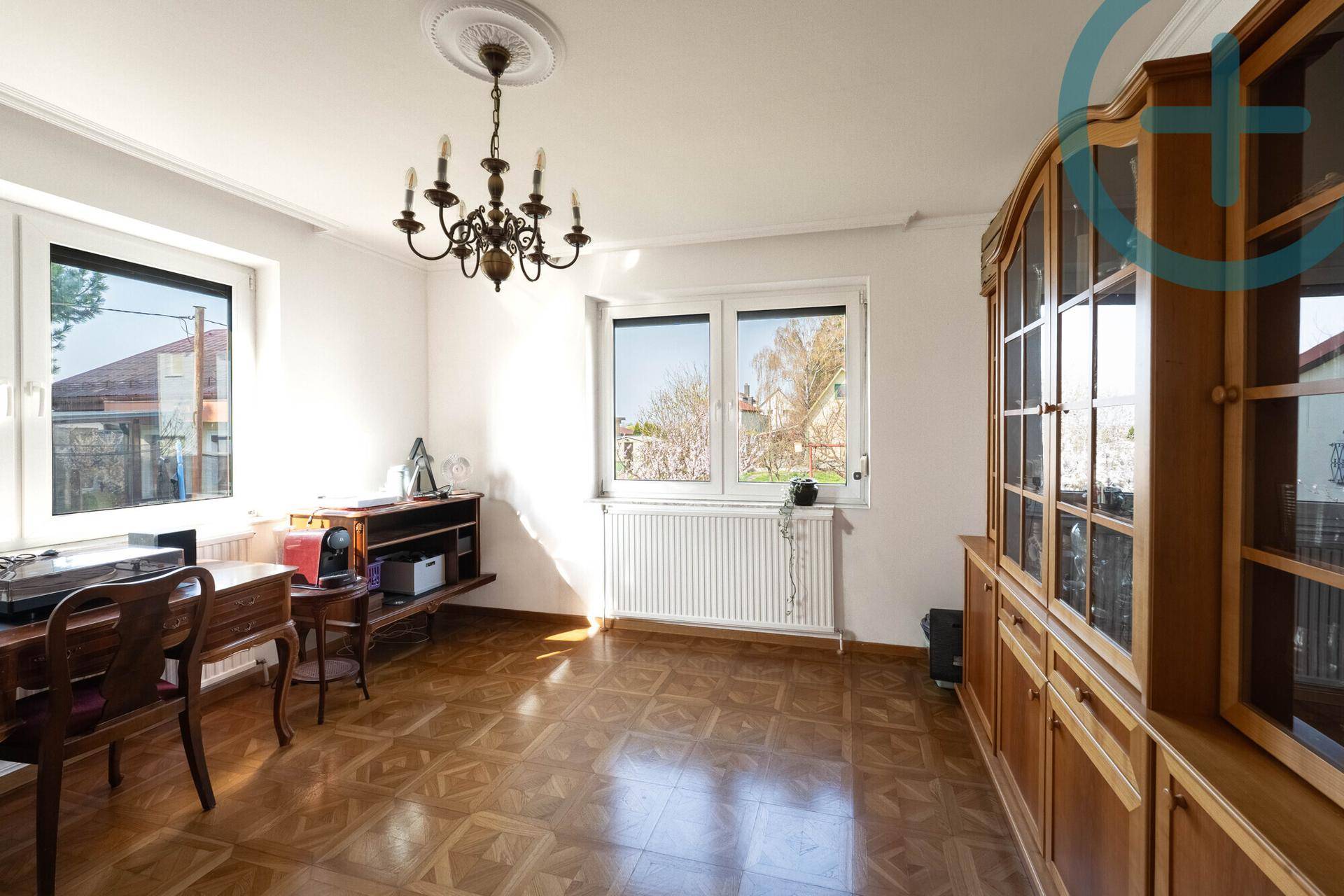 Helles Zimmer mit Parkettboden, Stuckdecke und Blick ins Grüne.
