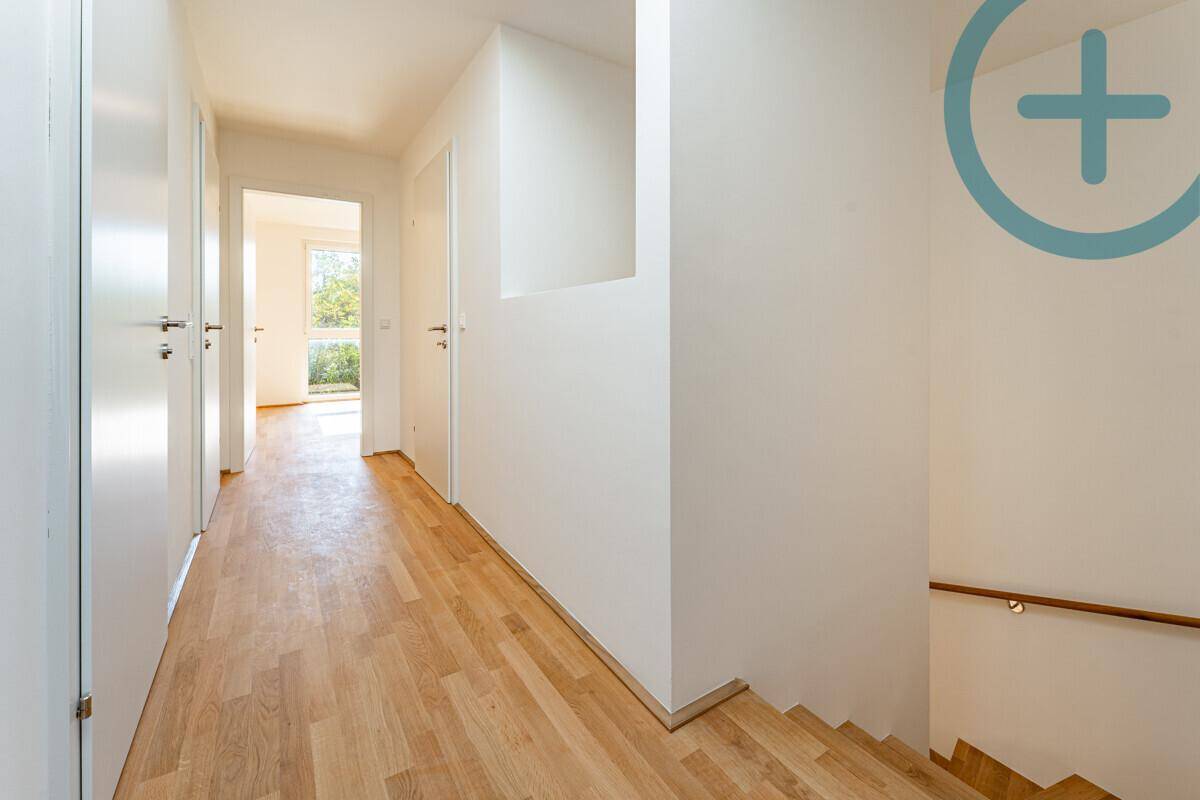 Heller Flur mit Parkettboden, mehreren Türen und Zugang zu einer Holztreppe.